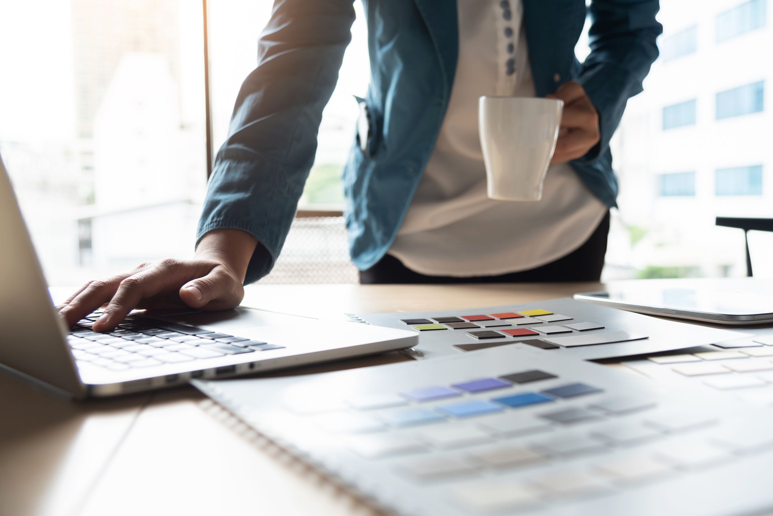 creative designer working with laptop with samples on table