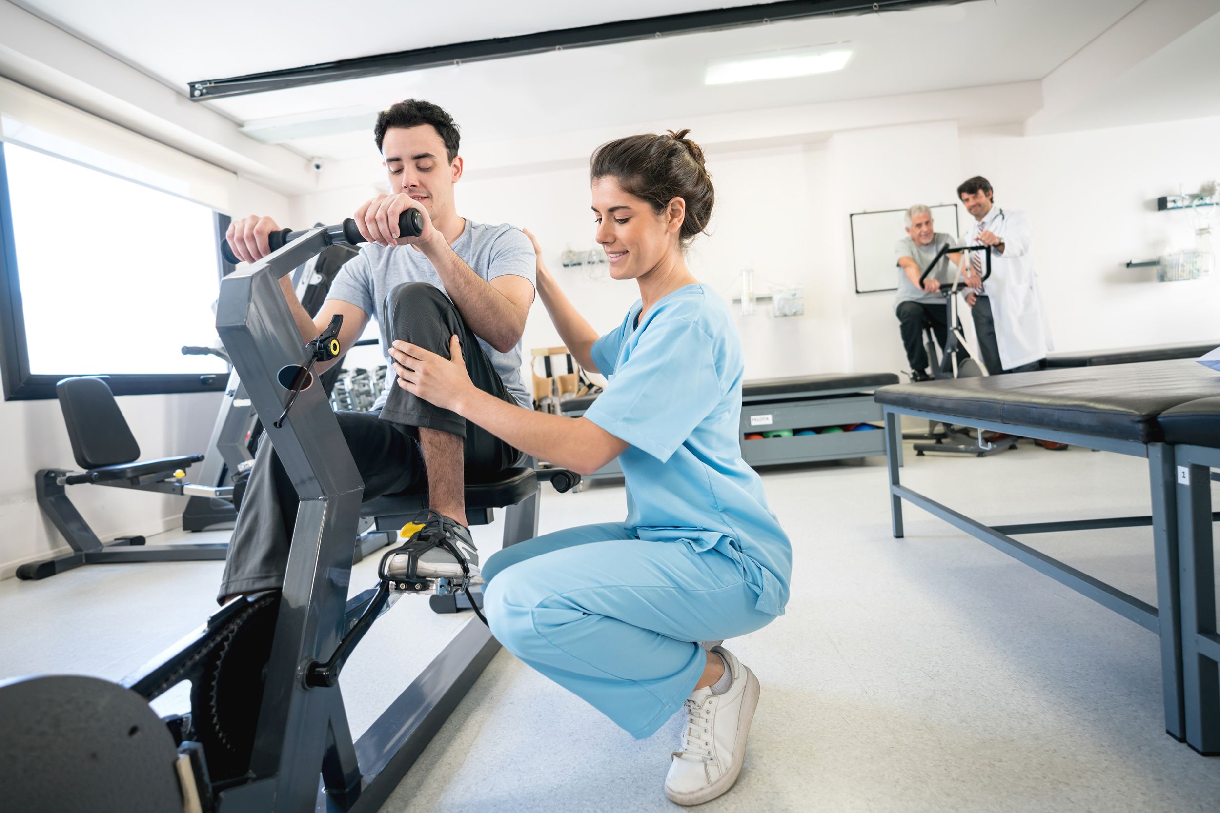 physiotherapist correcting the posture of a patient on a static bicycle