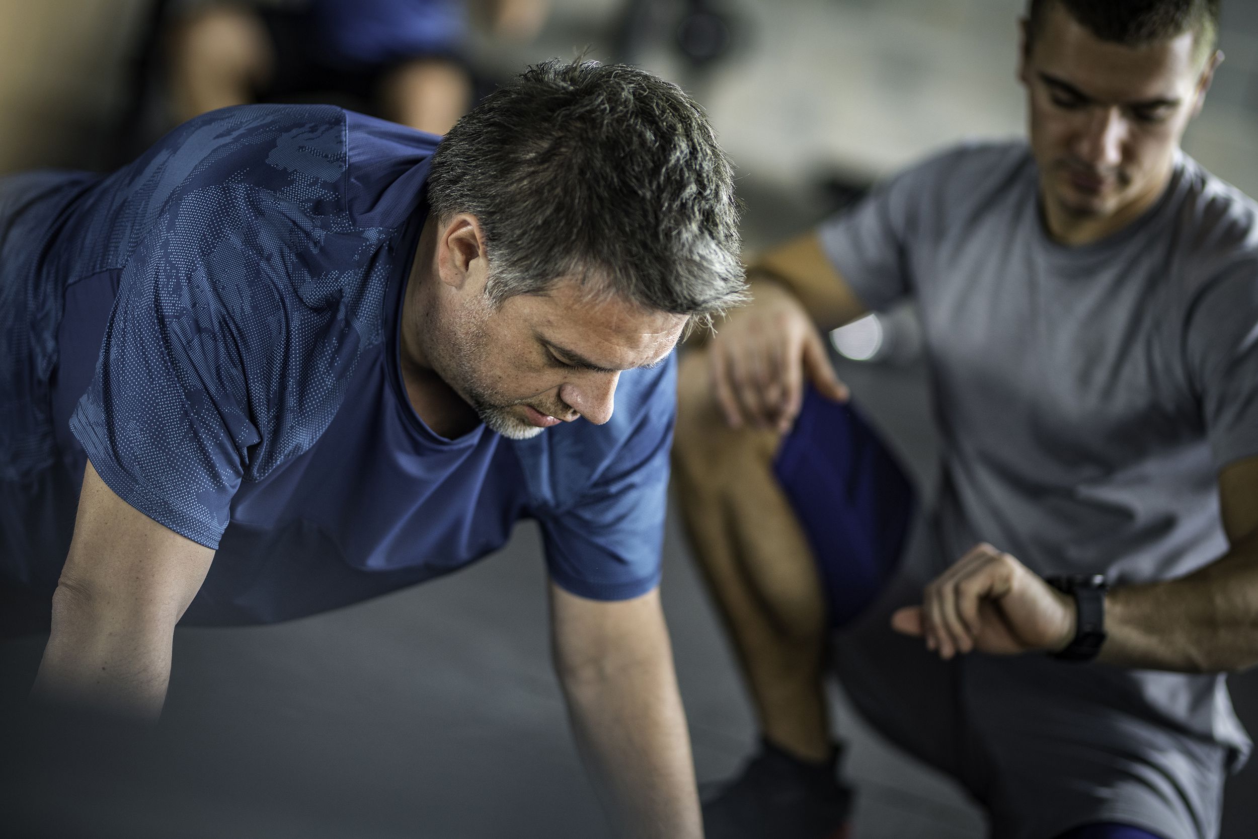 personal trainer timing his client in a plank position
