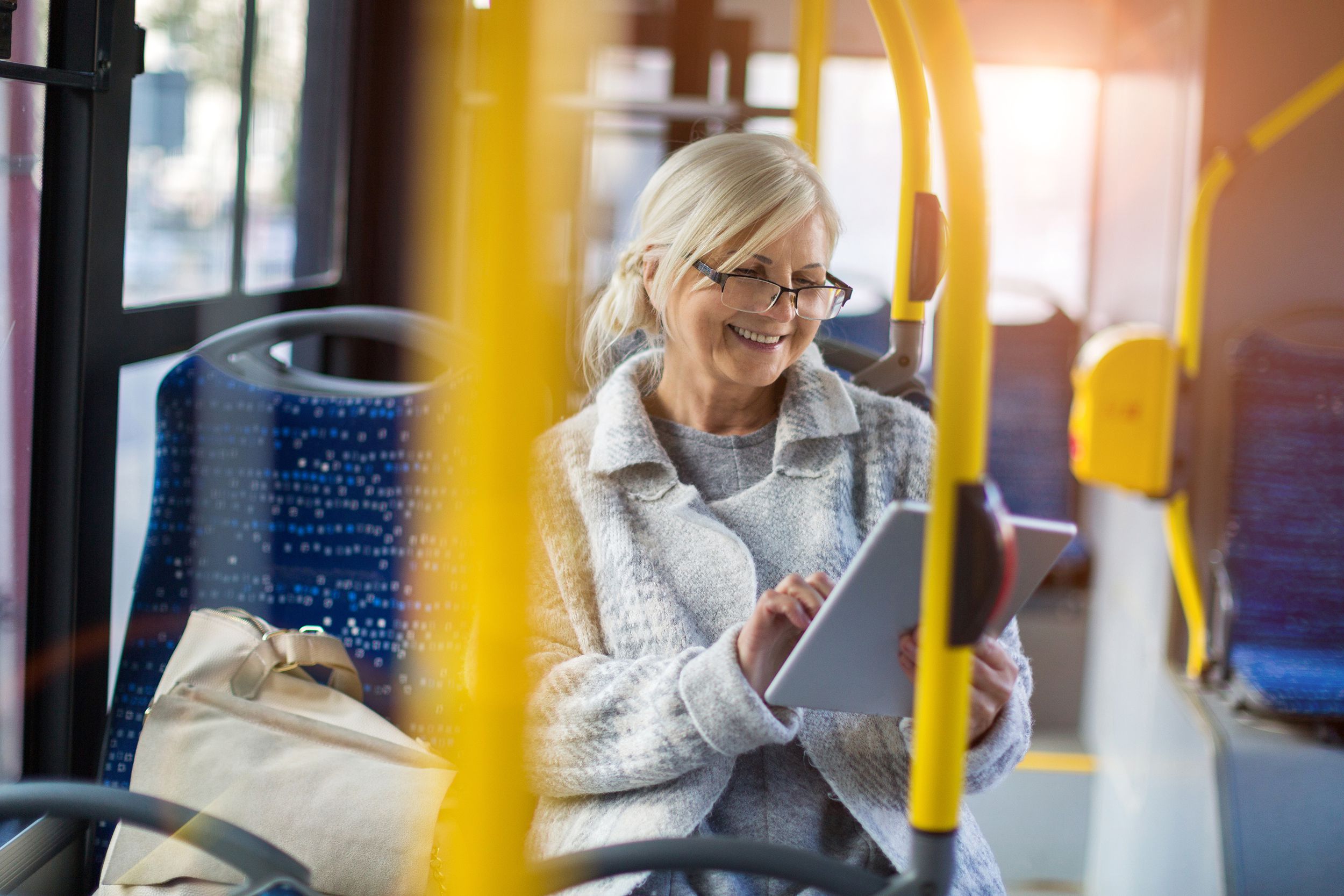 senior woman in transit bus using digital tablet