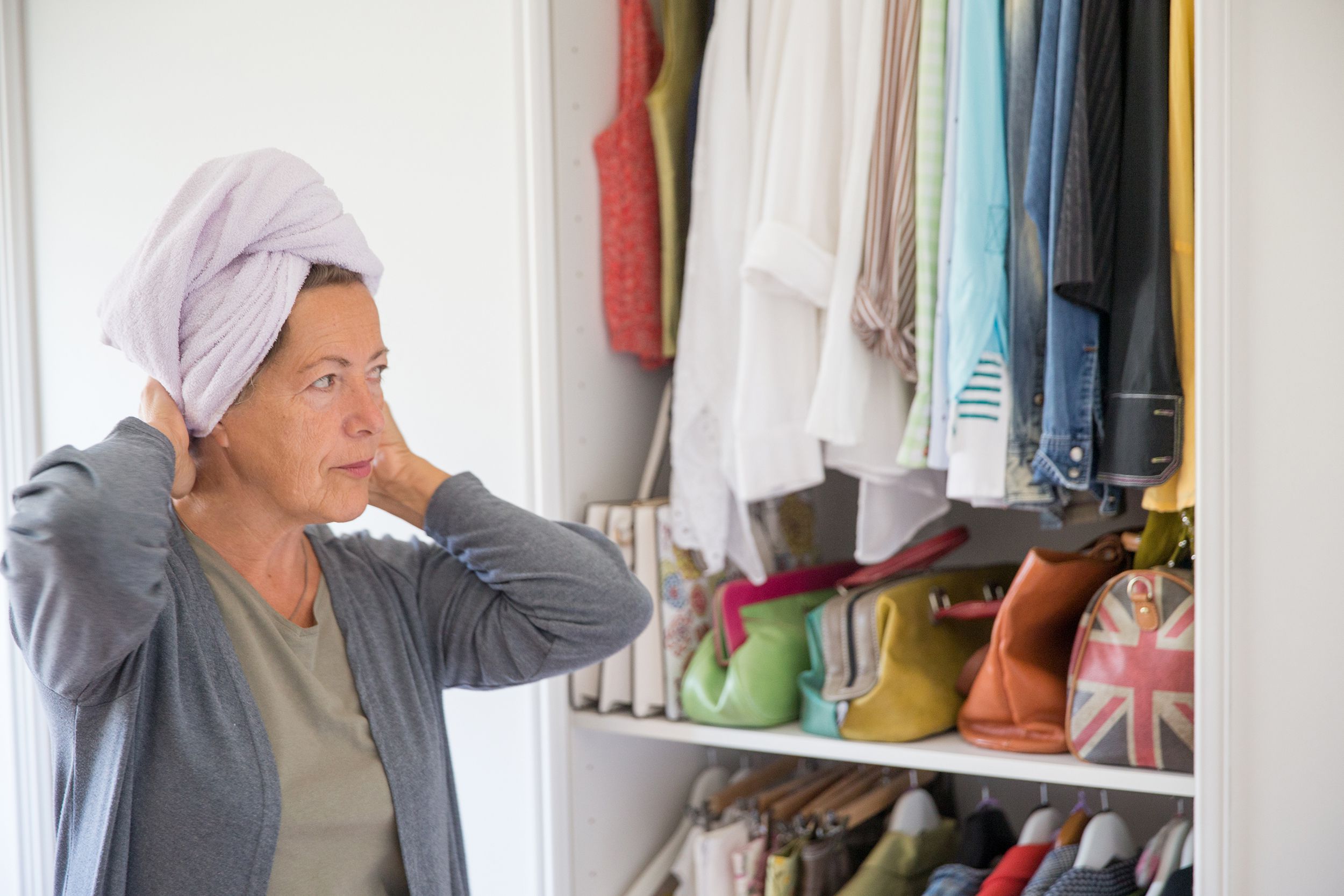 pensive senior woman looking at closet deciding on what to wear