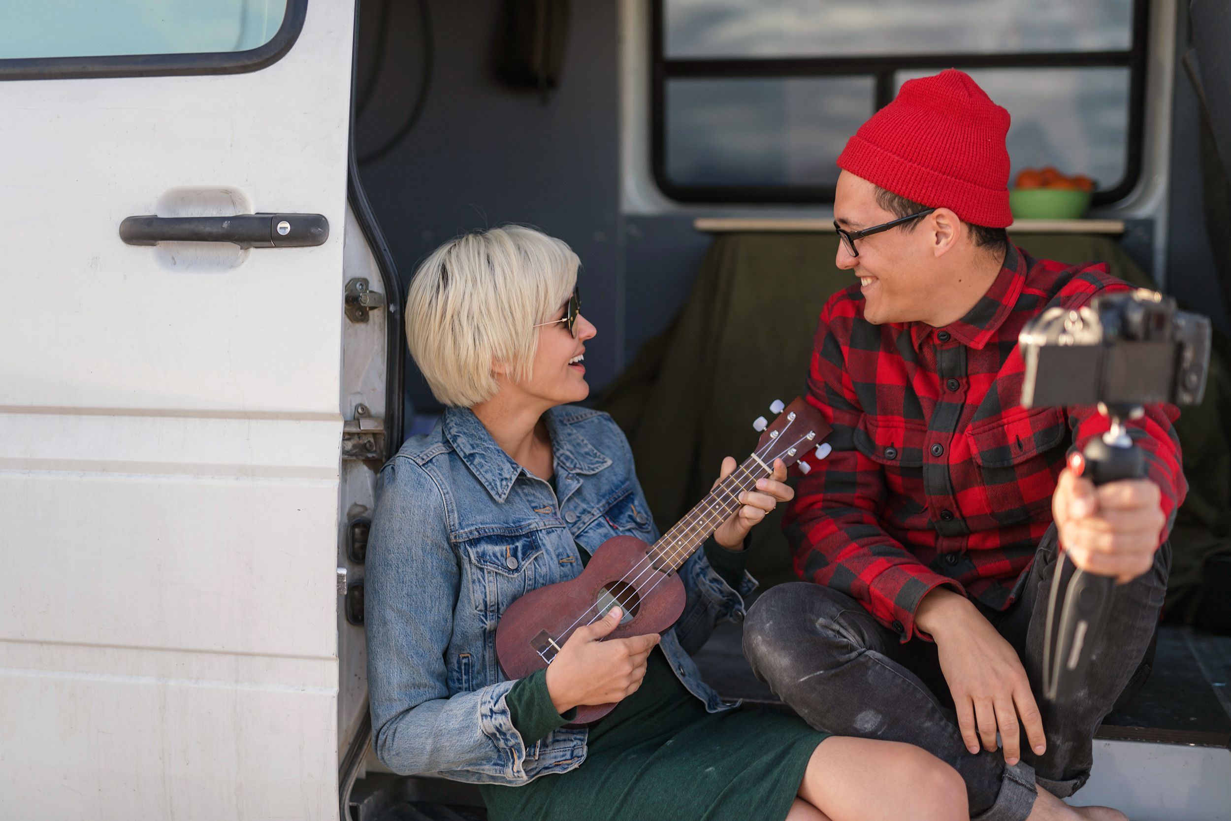 couple vlogging while sitting on the step of their rv van