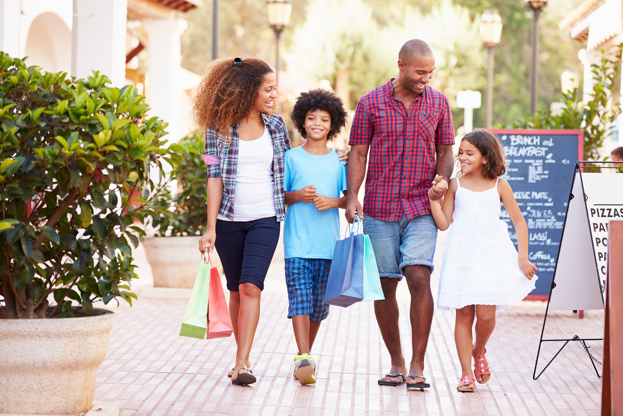 family walking along street with shopping bags