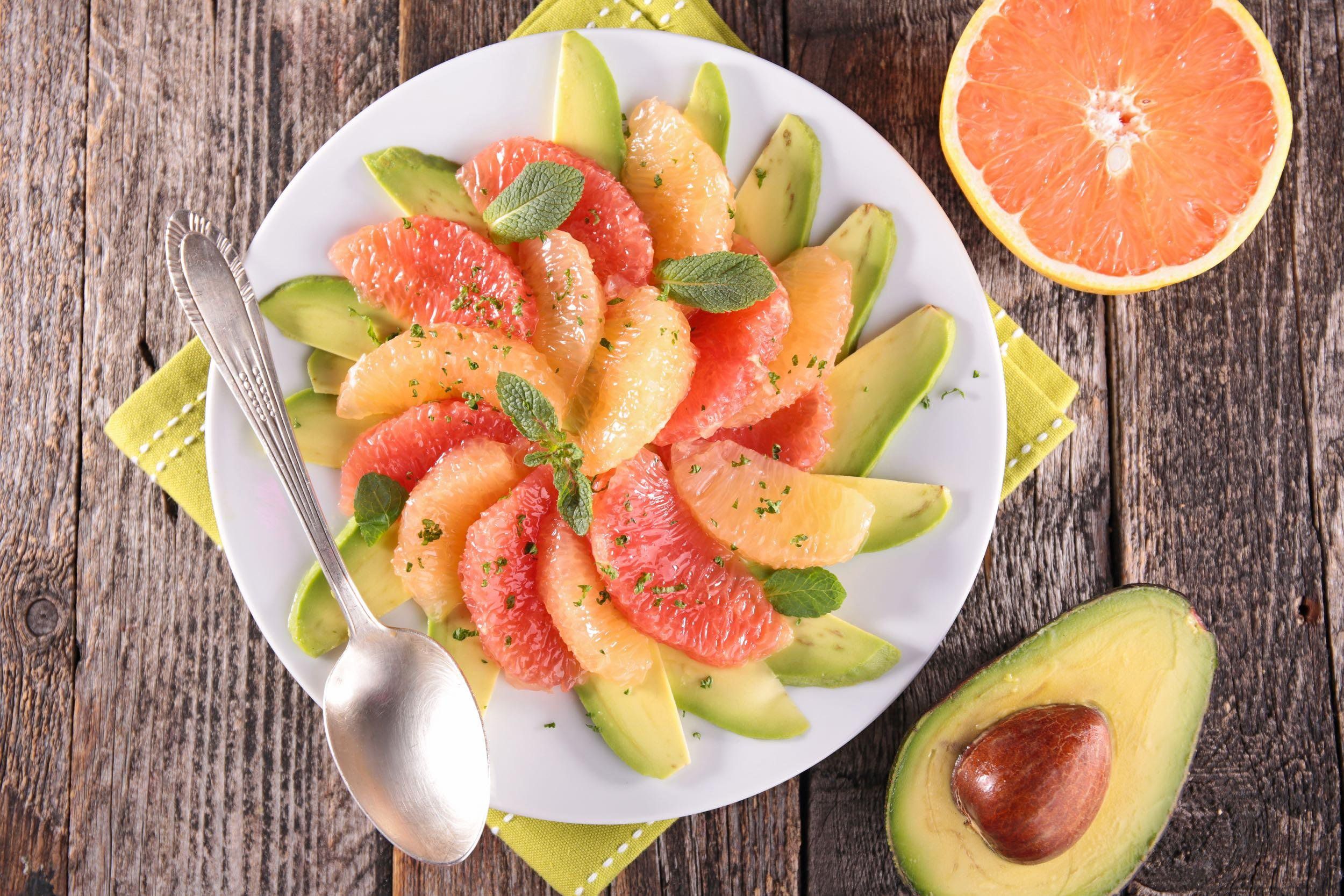 Avocado grapefruit salad on a white plate on a rustic wood background