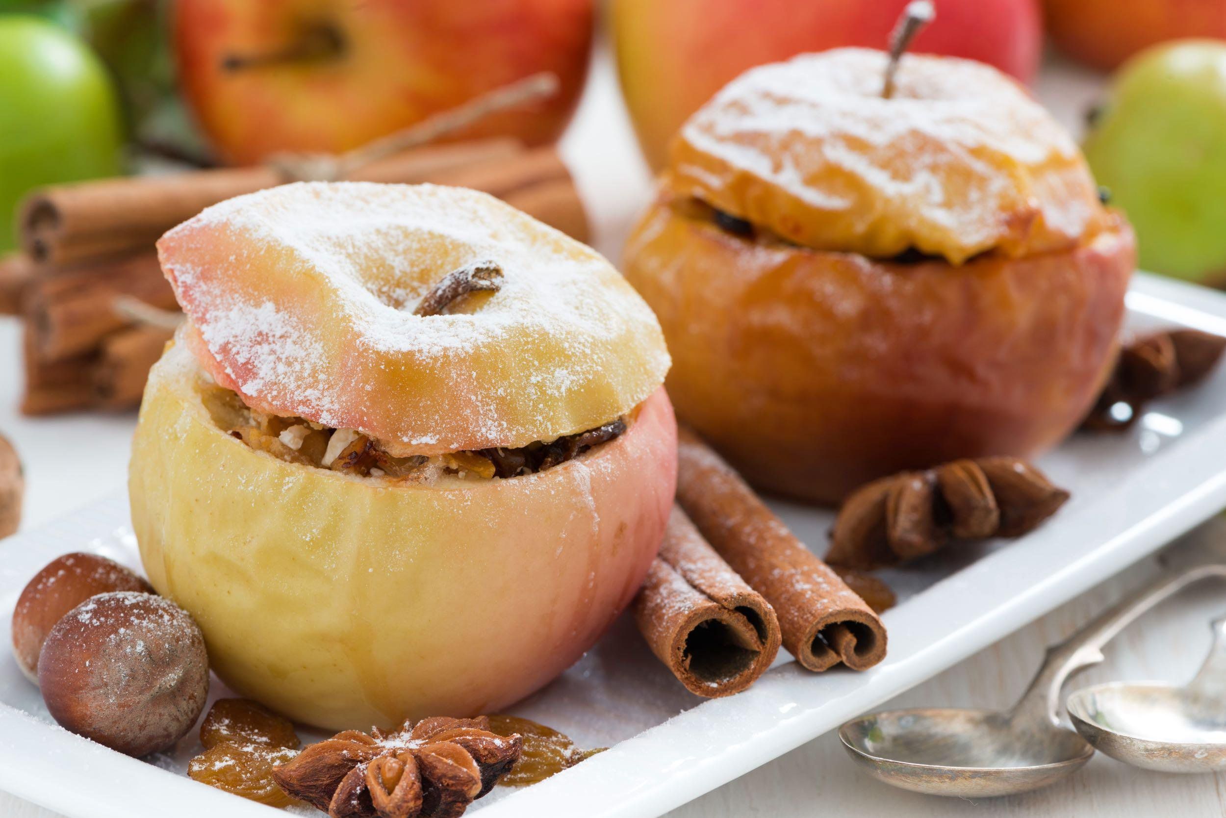 Baked apples with cinnamon and nuts on white serving platter
