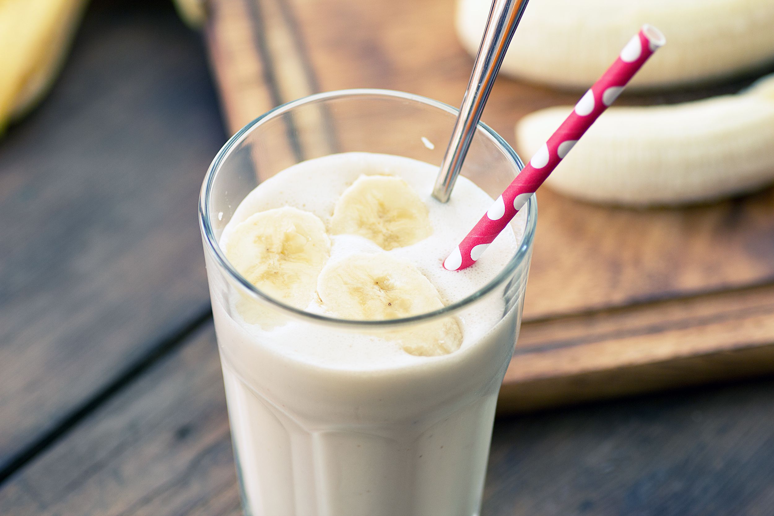 Banana Nut Smoothie in a tall clear glass with a pink polka dot straw