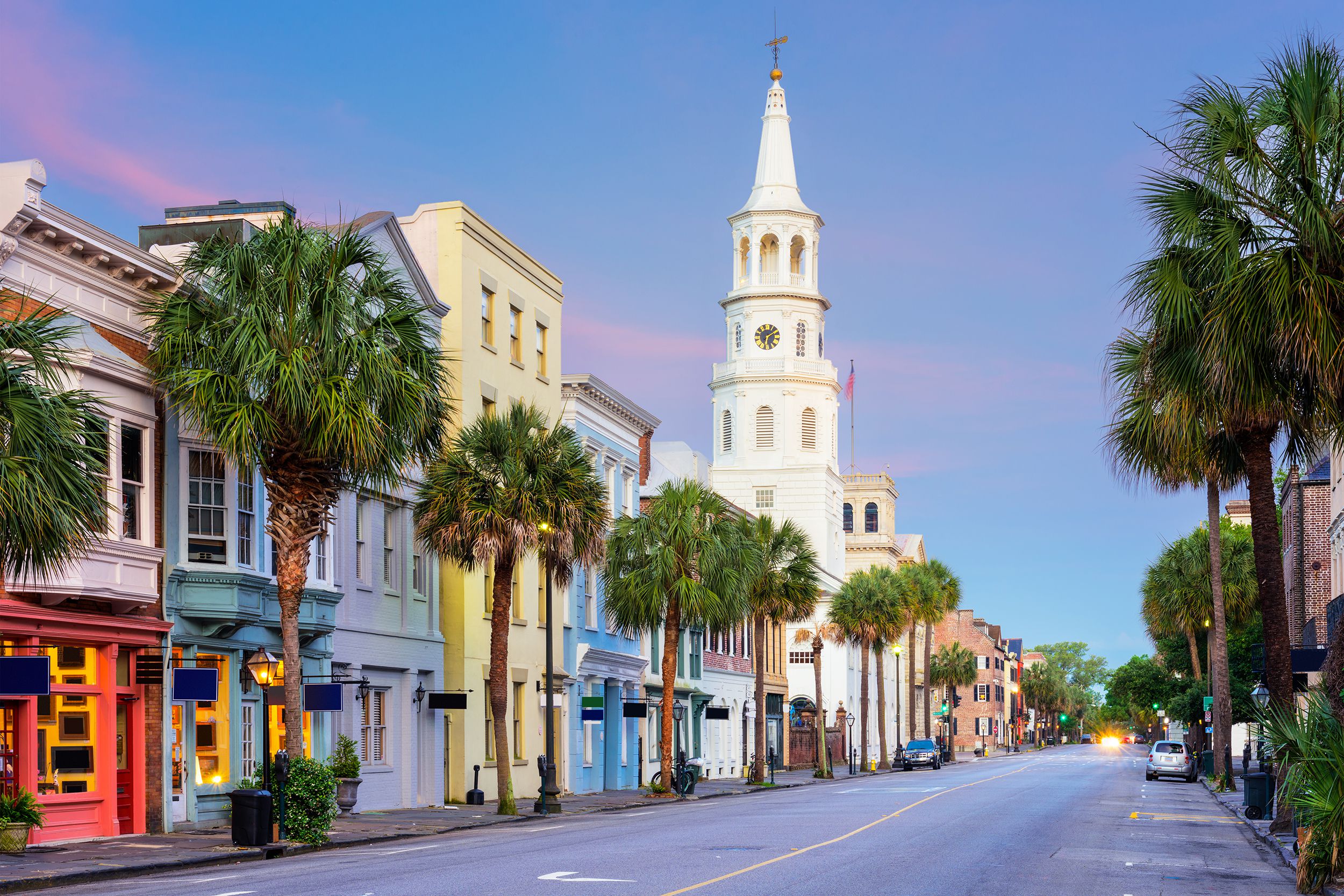 Colorful buildings and palm trees line the street of the French Quarter, Charleston, South Carolina at dawn, almost empty street, a dark blue sky with pink clouds in the background