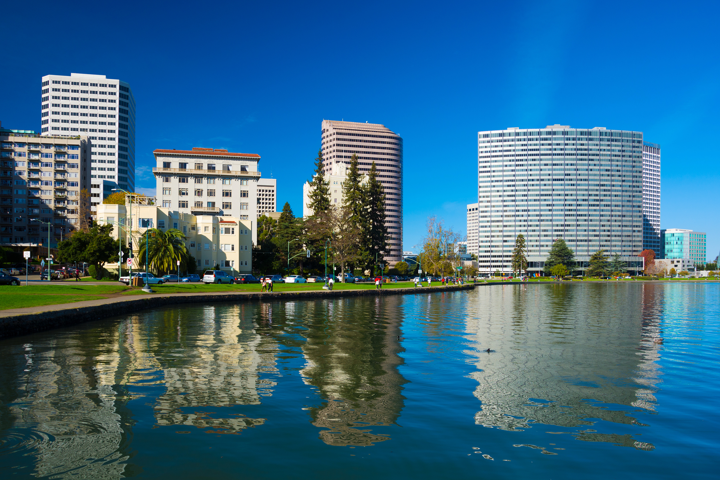 Lake Merritt and buildings of Oakland, California, lake in the foreground with park and buildings in the distance, with a clear blue sky
