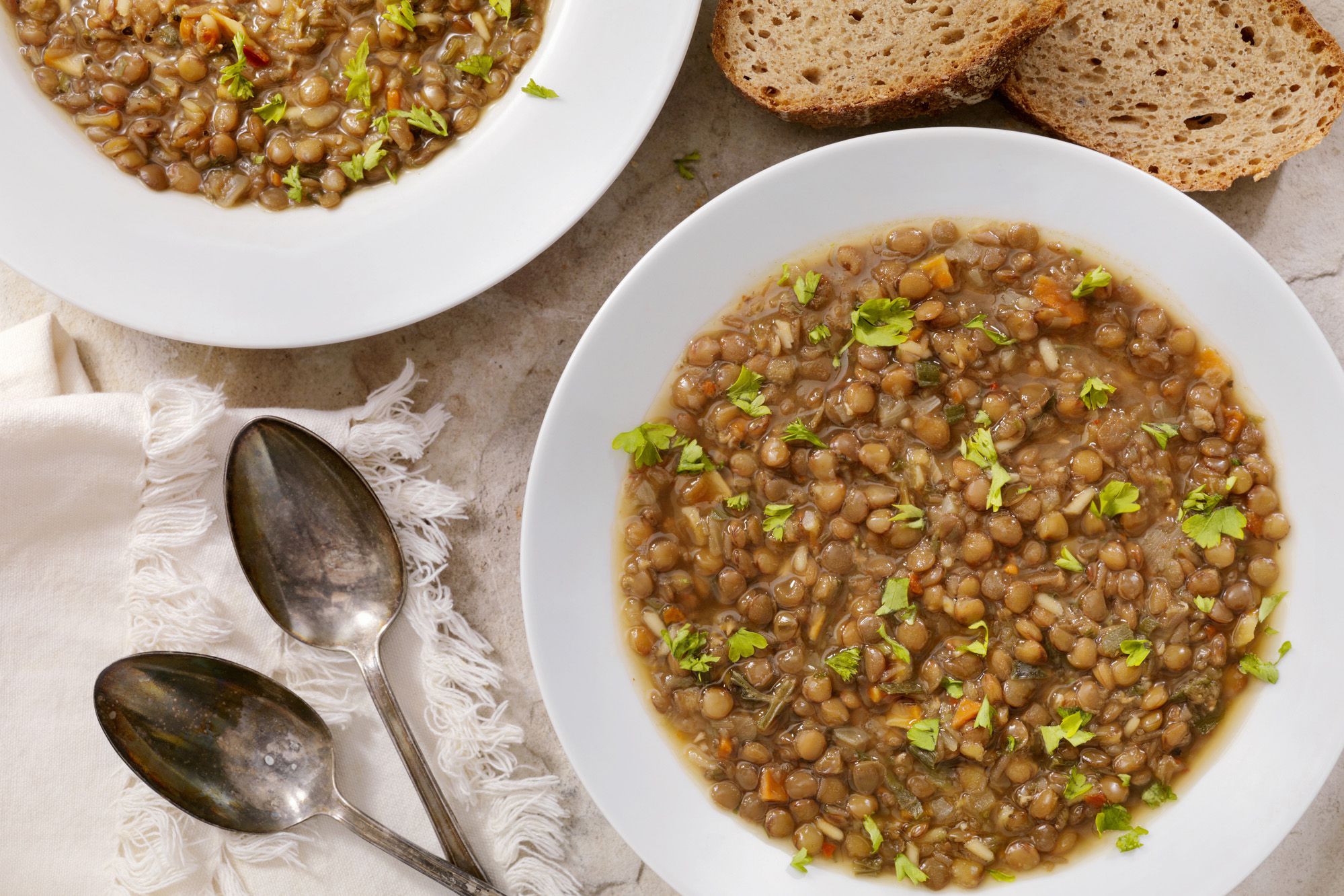 Two pieces of bread and two bowls of lentil soup