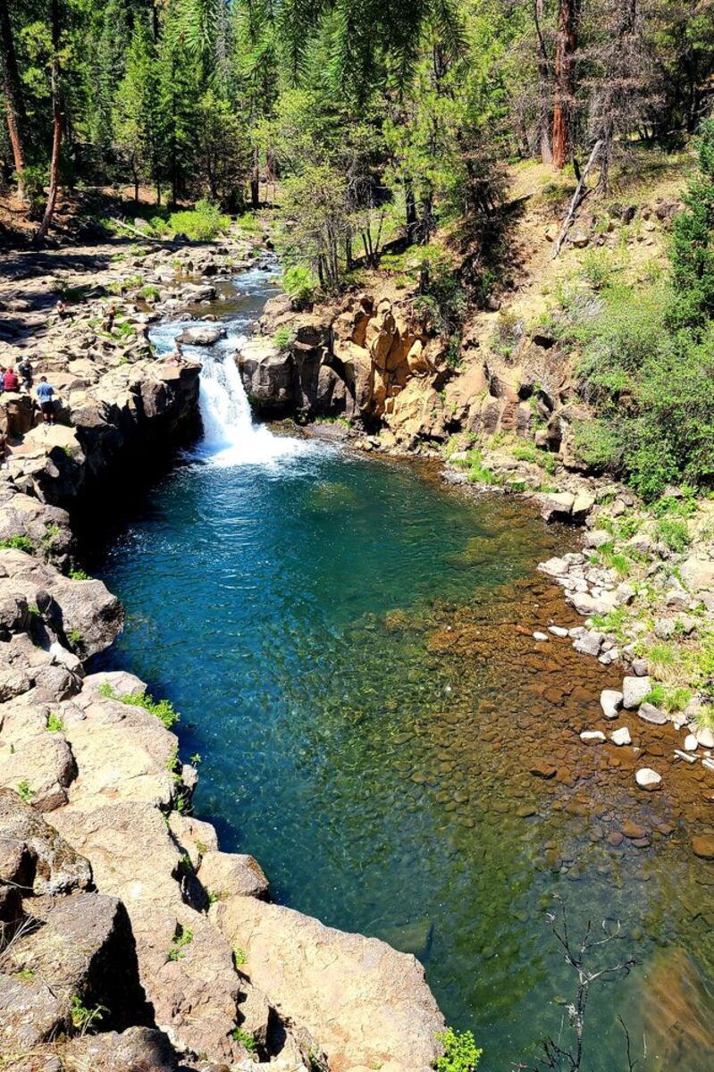 Lower McCloud Falls, Redding, California, waterfall in the background with swimming hole in the foreground surrounded by rocks and forest
