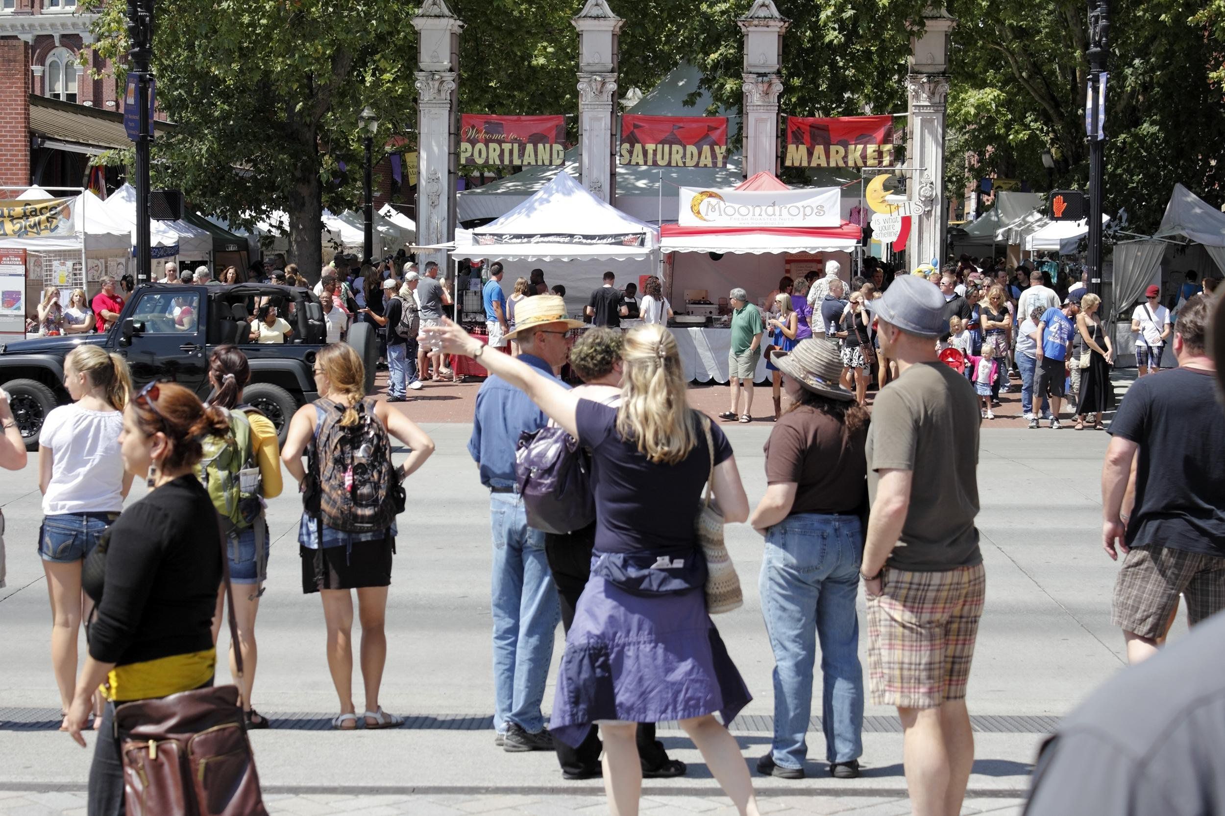 Many people waiting to cross SW Naito Parkway near the waterfront at the Portland Saturday Market, Portland, Oregon, on a sunny summer day