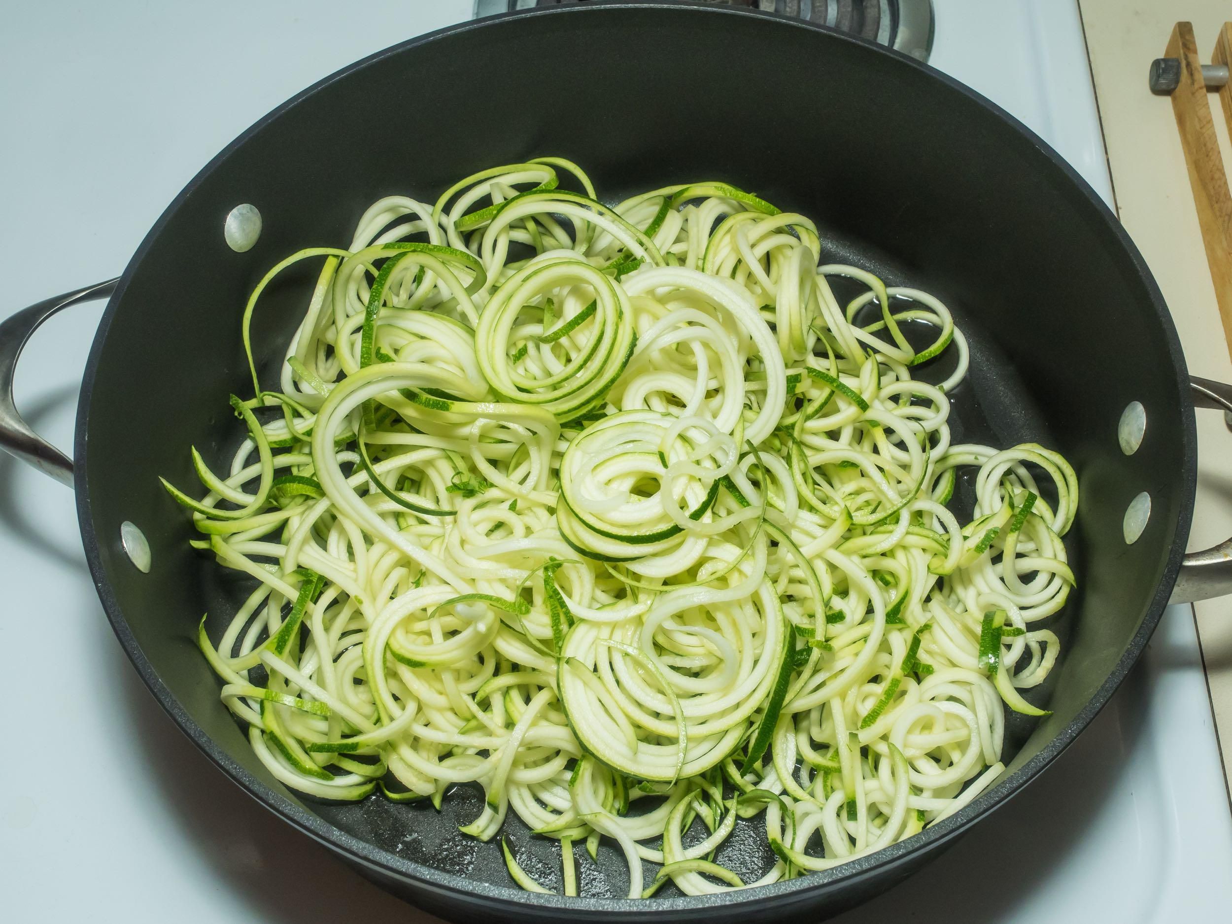 Raw zucchini spaghetti in a black frying pan