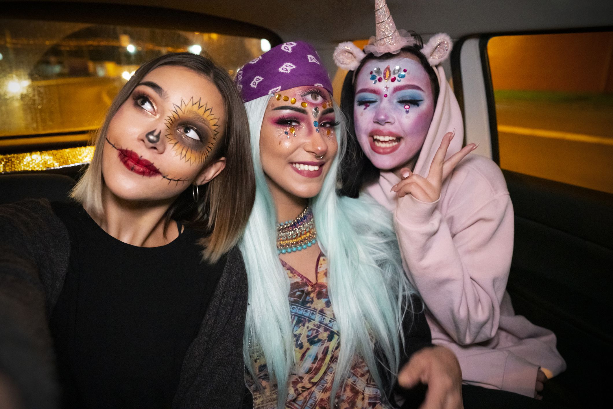 Girls riding in a taxi to the Halloween party and taking selfies.