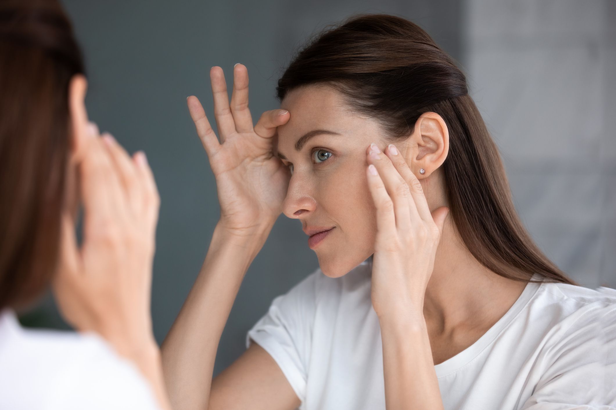 Close up of woman looking in mirror check face after mask cream beauty treatment feels satisfied admire reflection, laser skin resurfacing, glycolic acid peel, anti-ageing skincare procedures concept