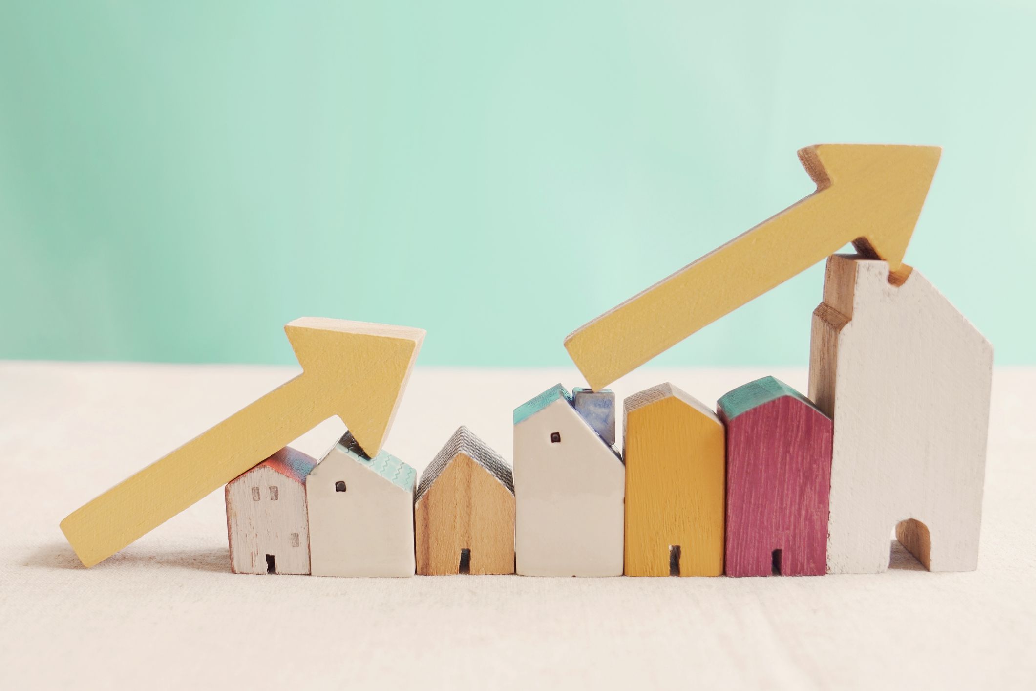 Wooden houses with yellow arrows up. housing boom, property market growing, high demand for real estate, house prices rising concept
