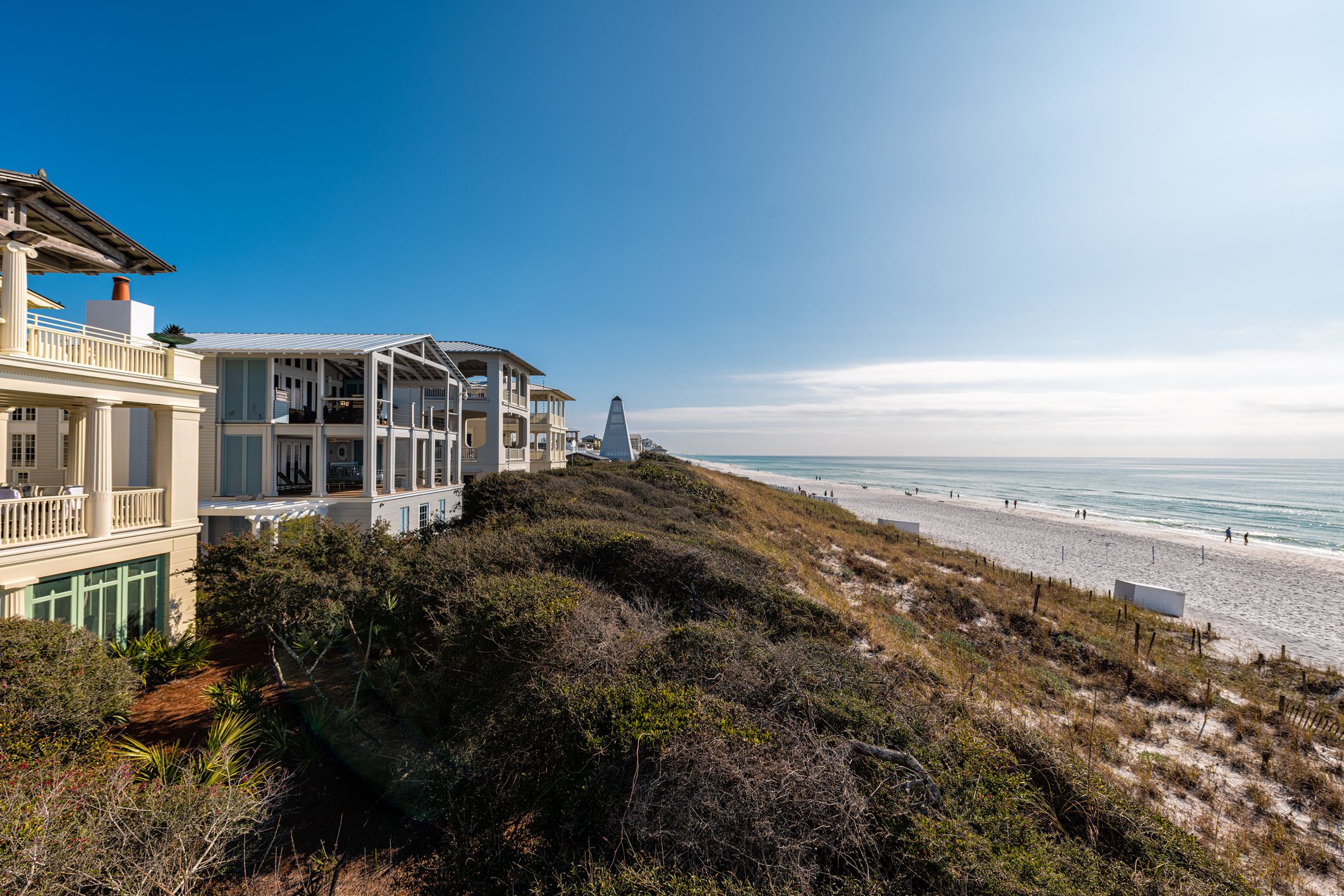 High angle view from wooden pavilion gazebo by beach at Gulf of Mexico at Seaside, Florida by new urbanism rental house home architecture with people walking on ocean sea coast