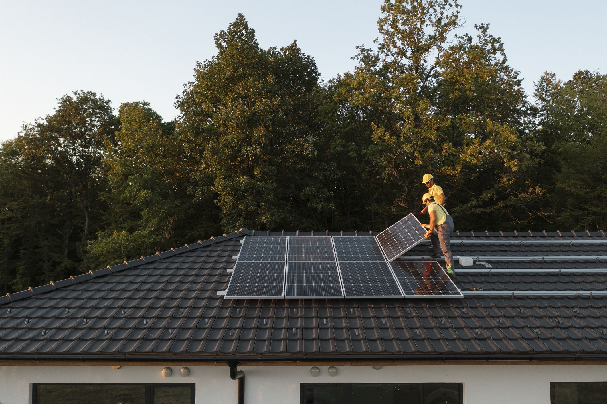 Two Professionalists Installing Solar Panels On A Roof Of A Modern House.