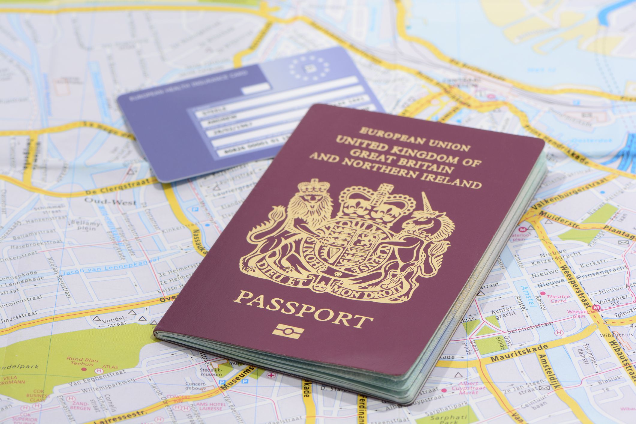 London, United Kingdom - December 12, 2013: Studio shot of a United Kingdom biometric passports and a European Union Health Card on a road map, One passport standing up and the other laying flat.