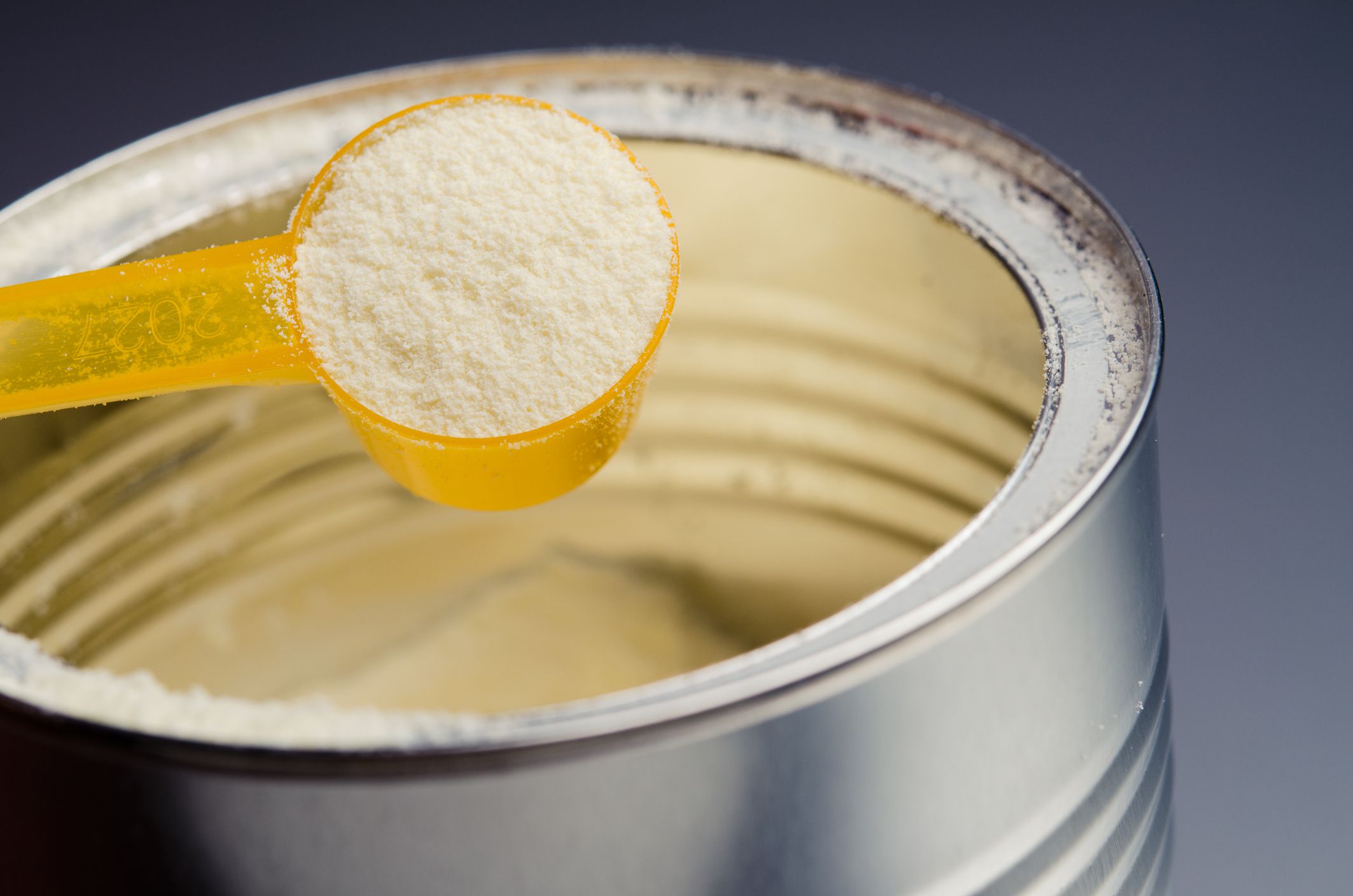 spoon with infant formula on background