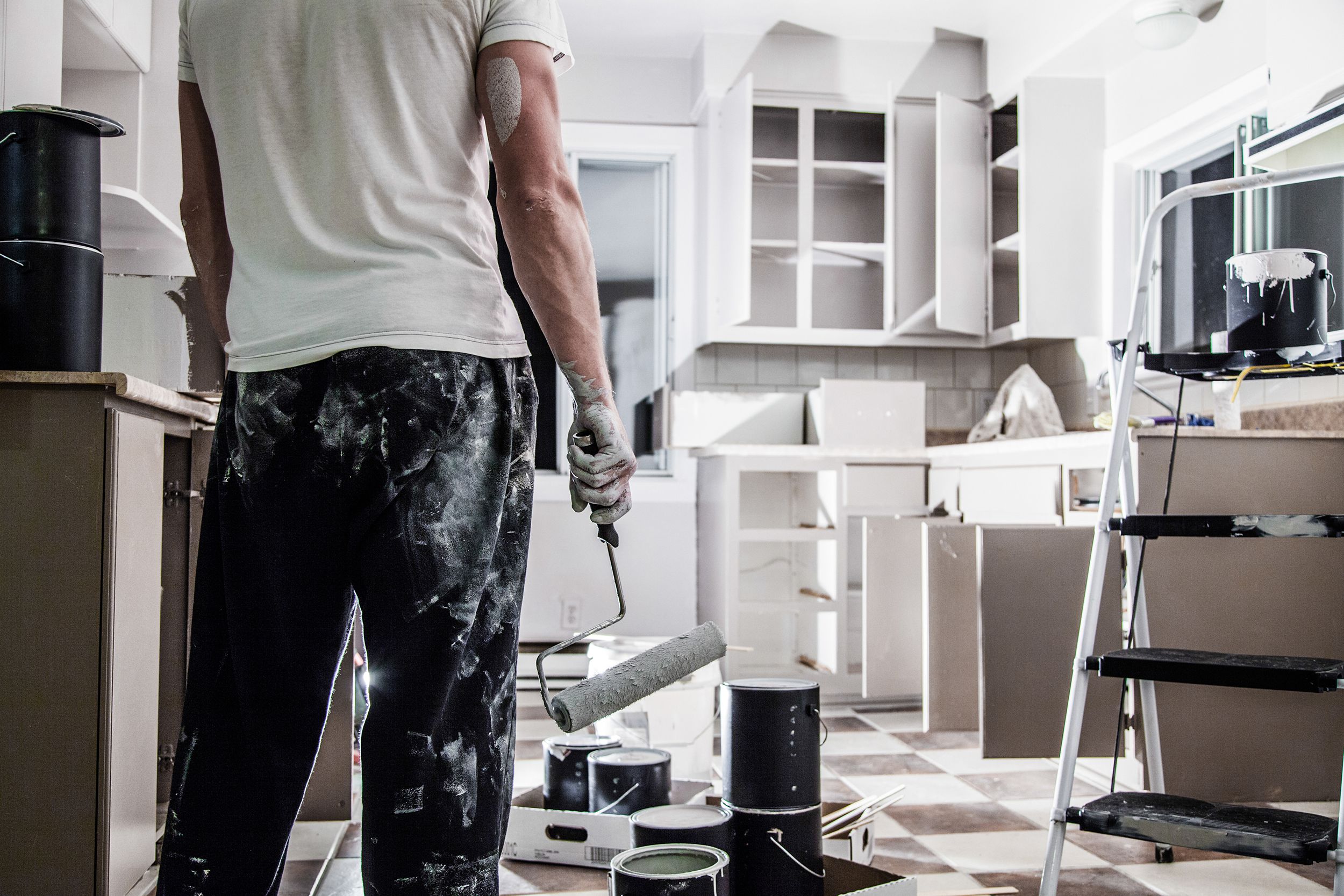 man taking a rest from painting, looking at newly painted kitchen