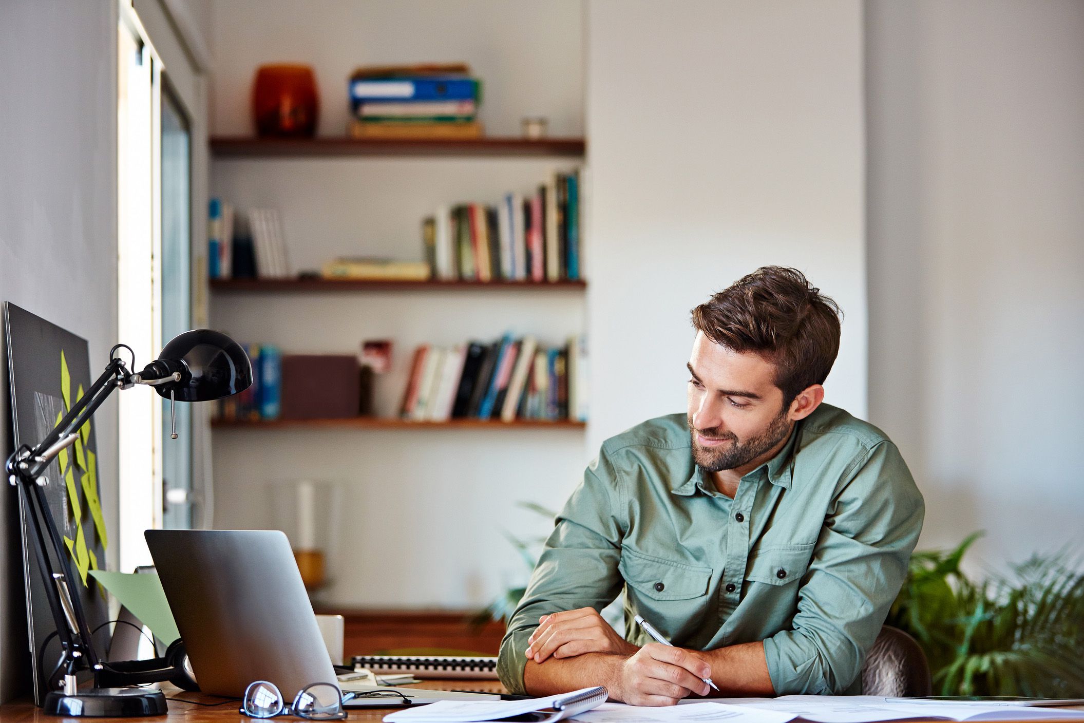man writing and editing document with laptop