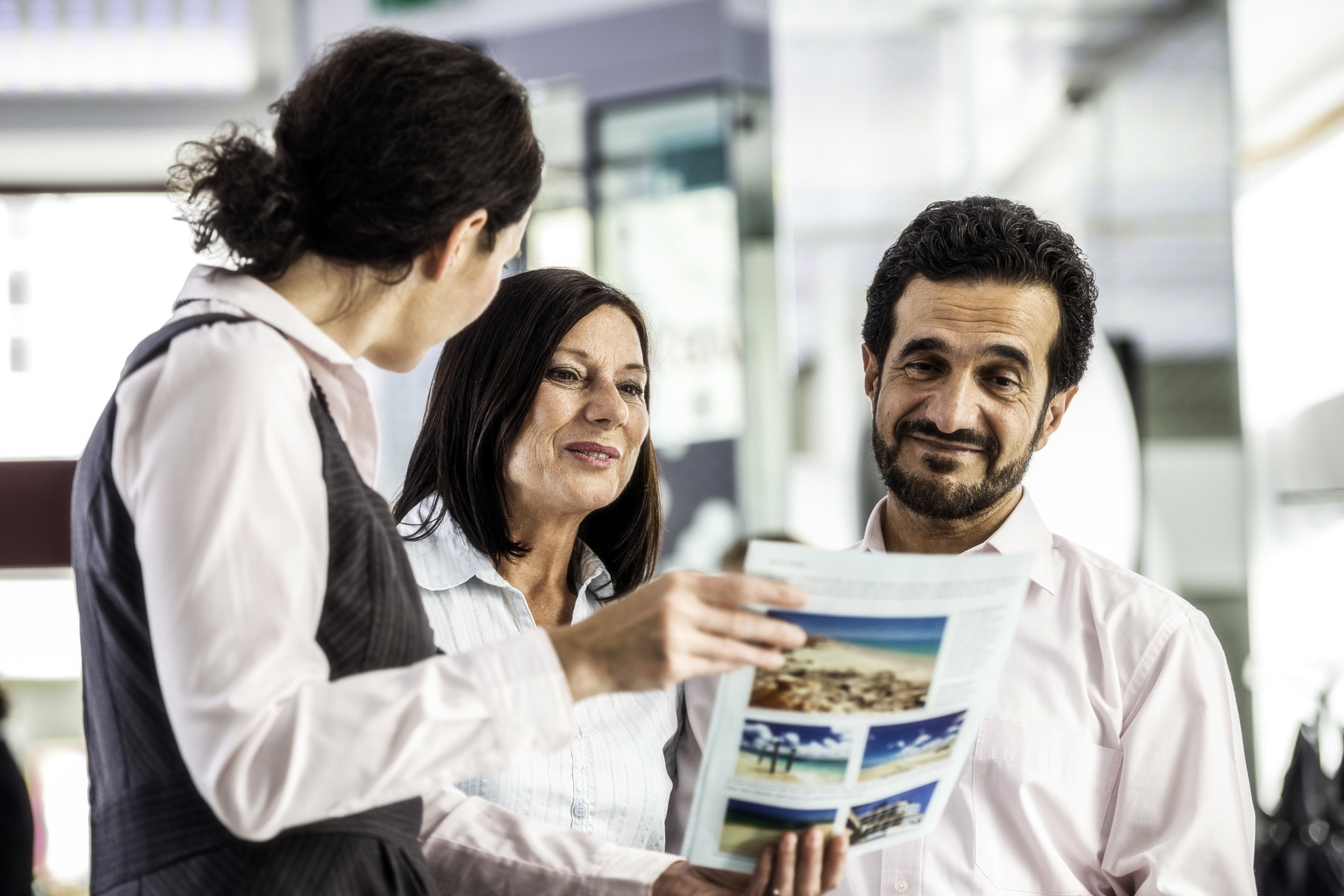 travel agent showing brochure to couple