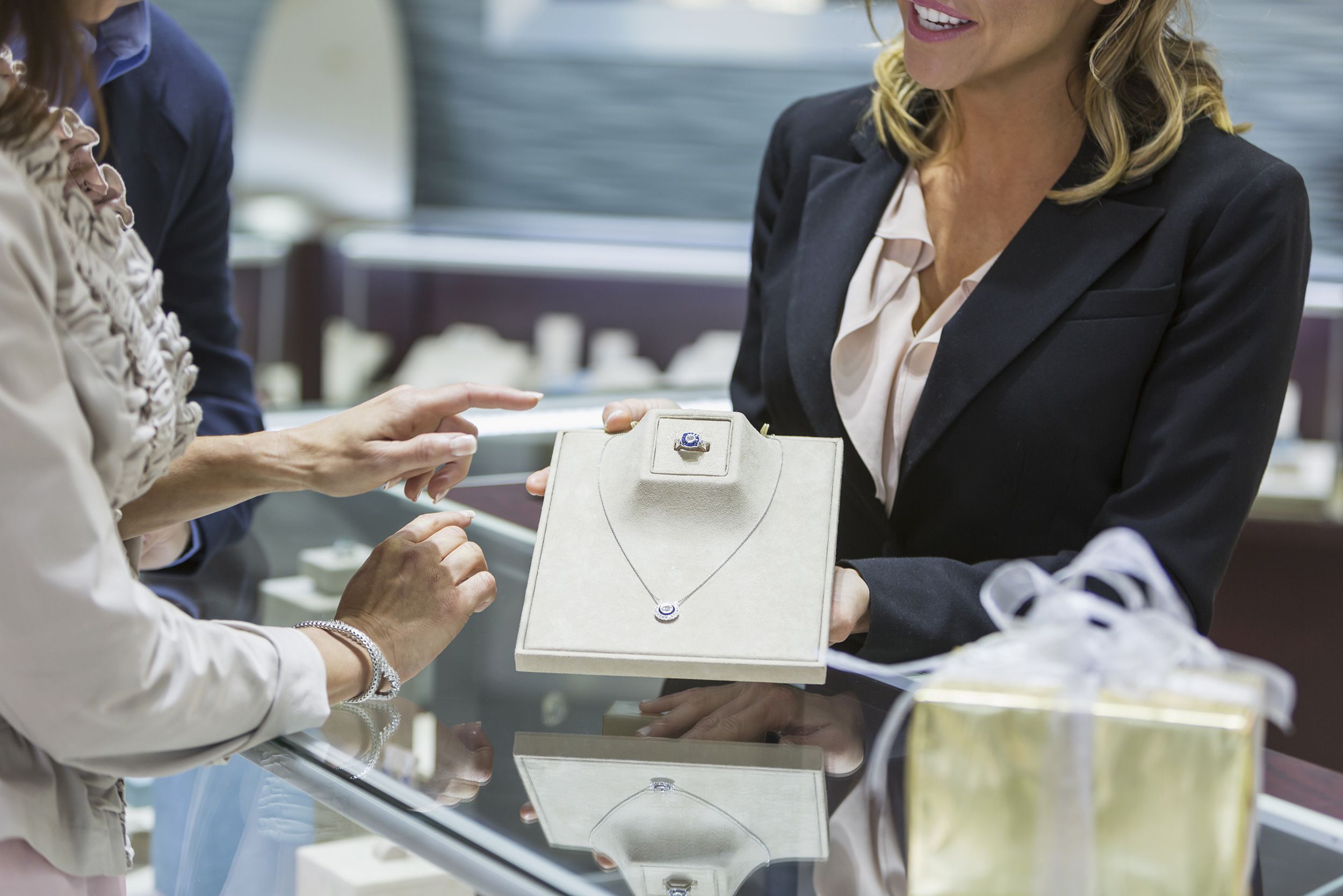 saleswoman helping couple in jewelry store