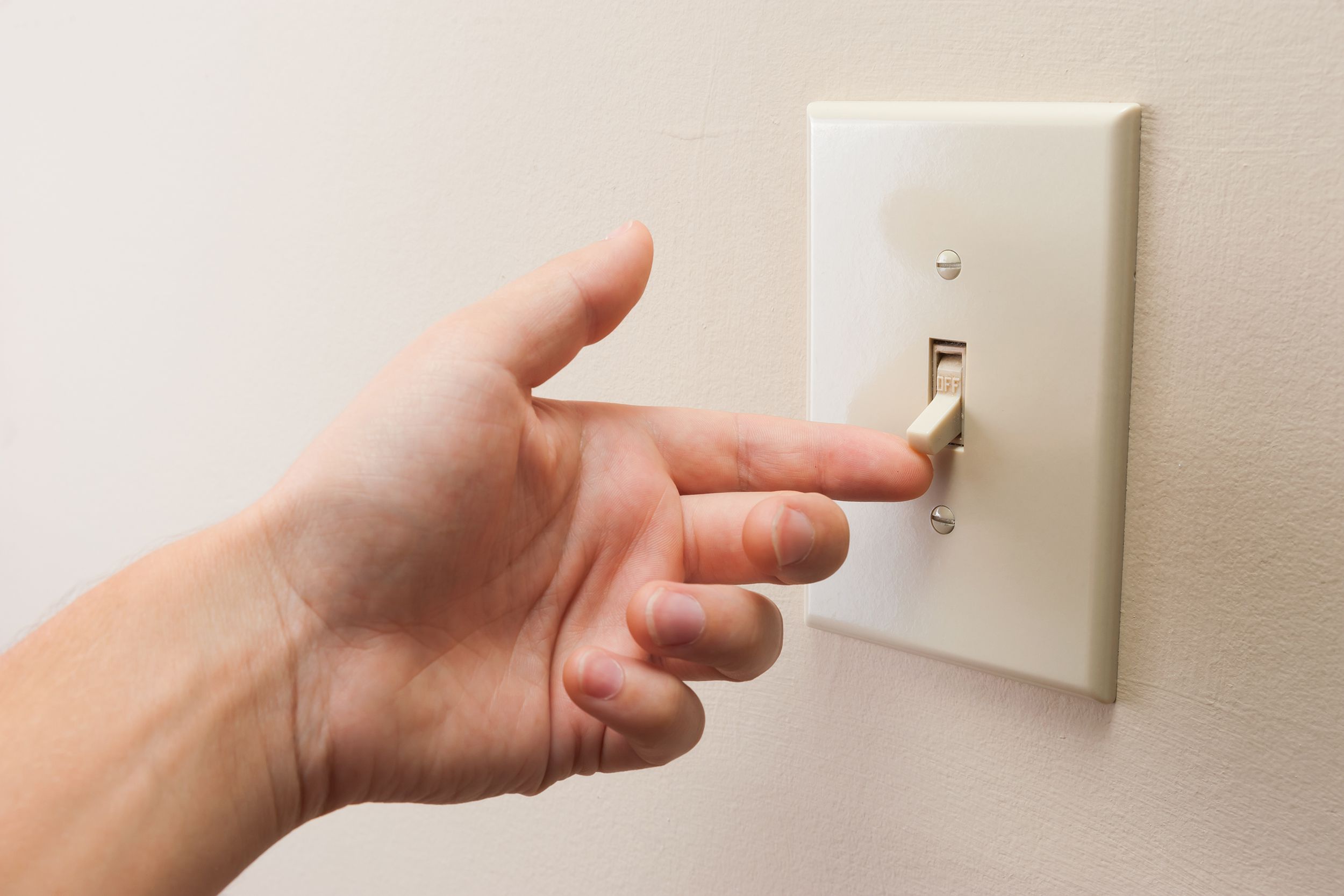 hand turning wall light switch off
