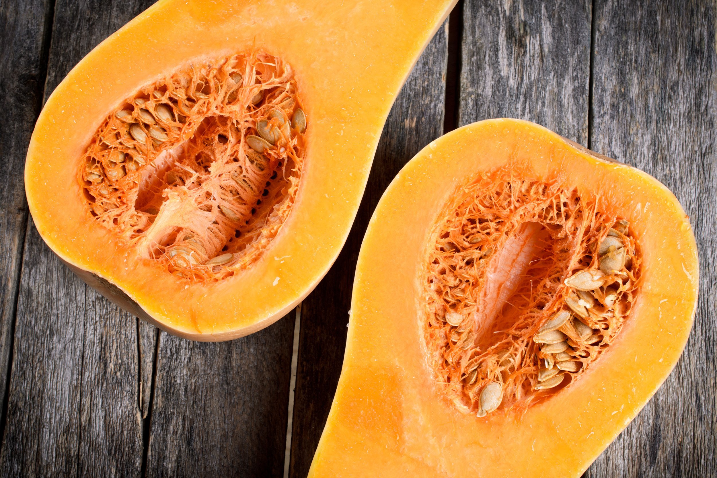 butternut squash cut in half on a wooden surface