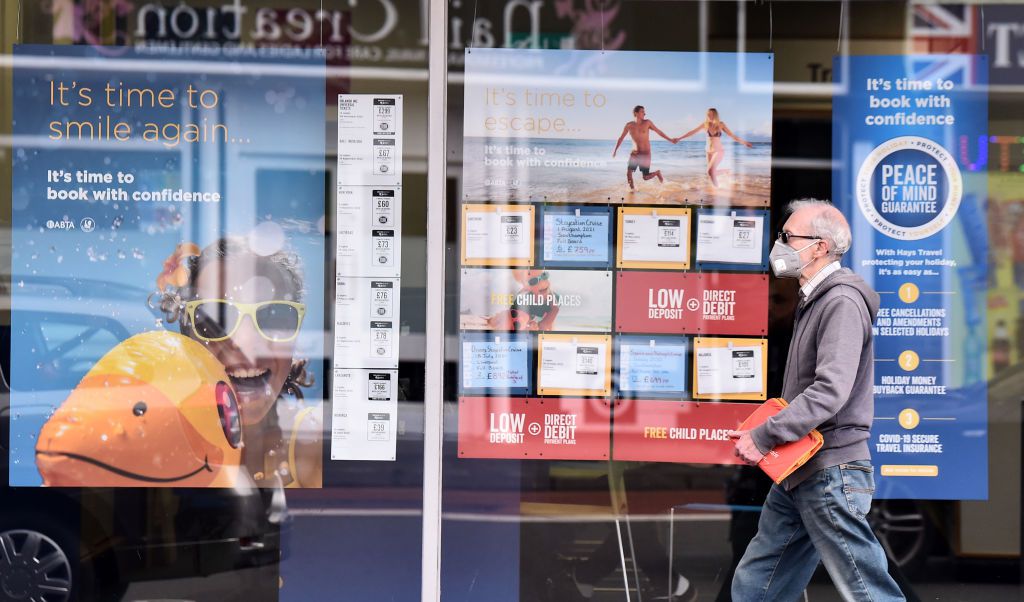 A man wearing a masks walks past a Hays Travel Agents on May 05, 2021 in Stoke-on-Trent, England