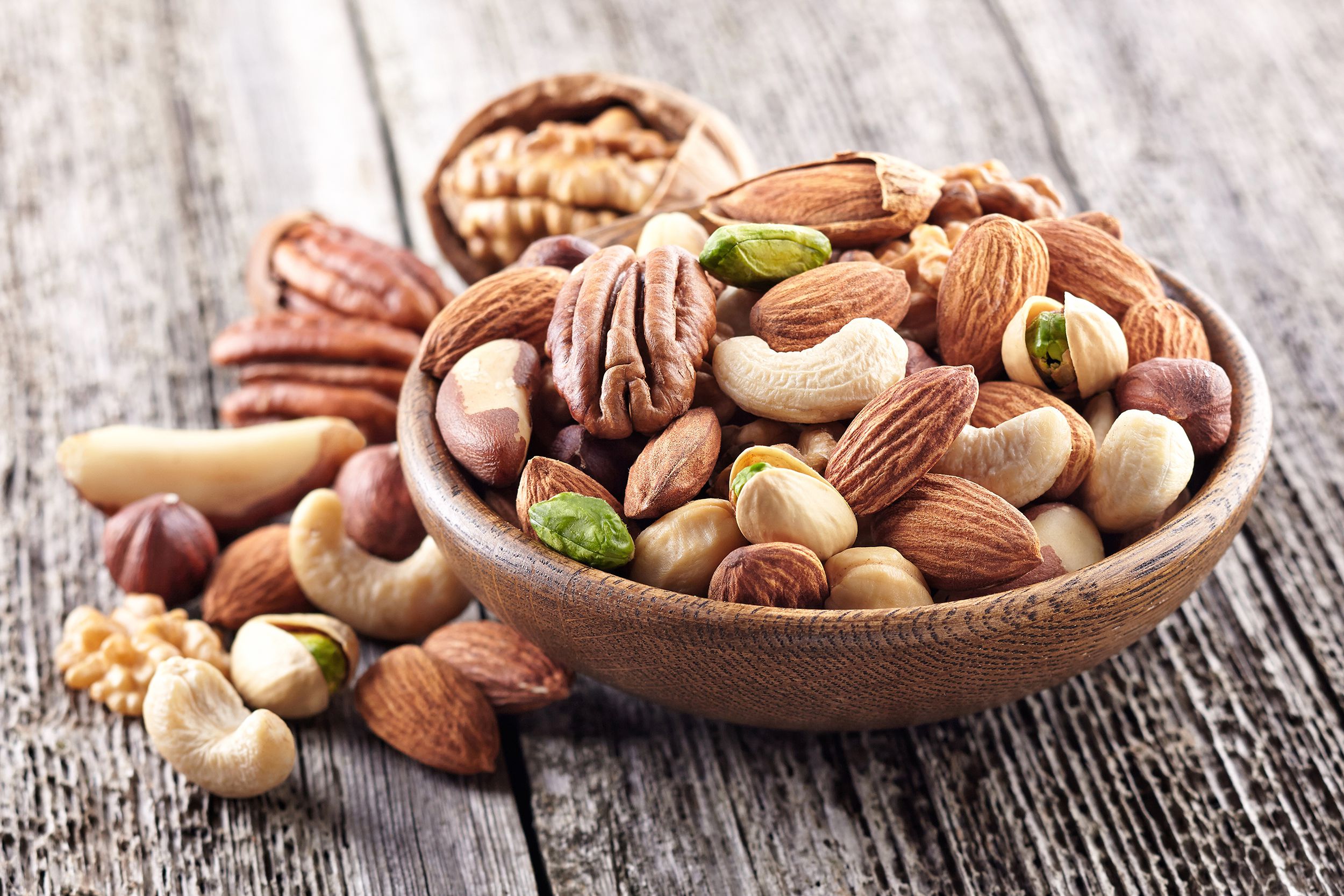 Mix of nuts in a wooden plate on a rustic table