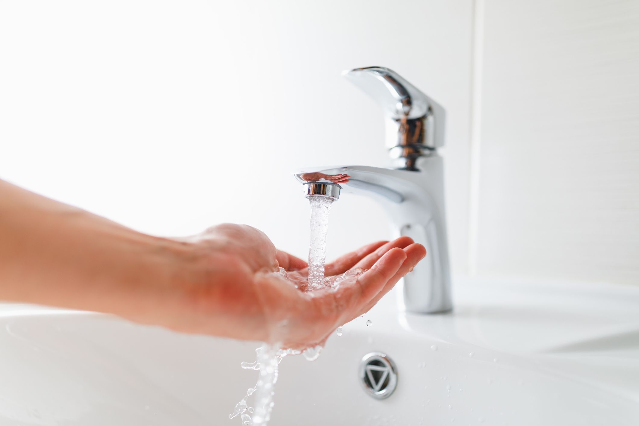 hand under faucet with water stream, close-up view