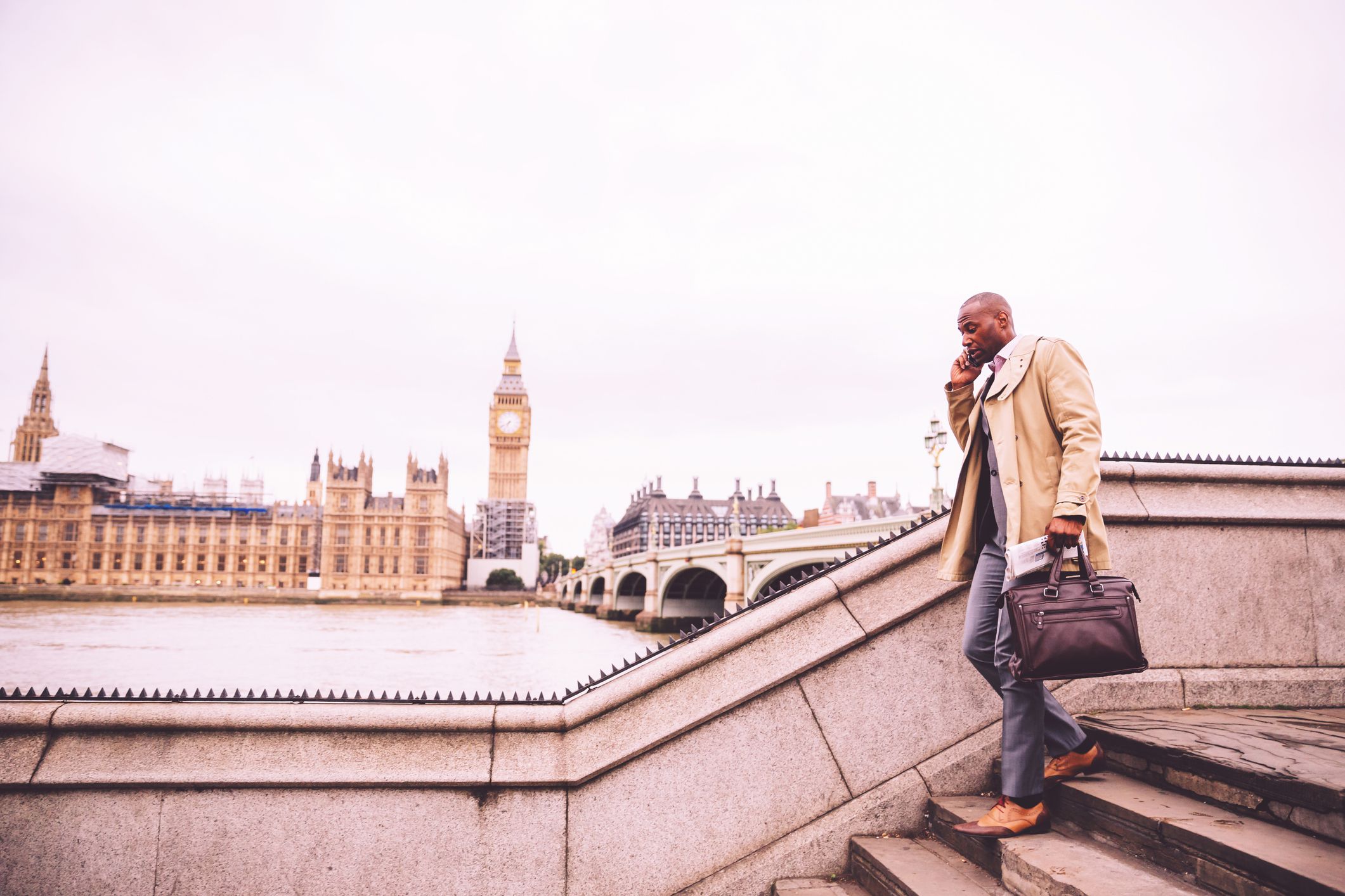 London, Businessman, Confidence, England - Busy Business Executive walking down the Westminster Bridge talking on the phone during his morning commute