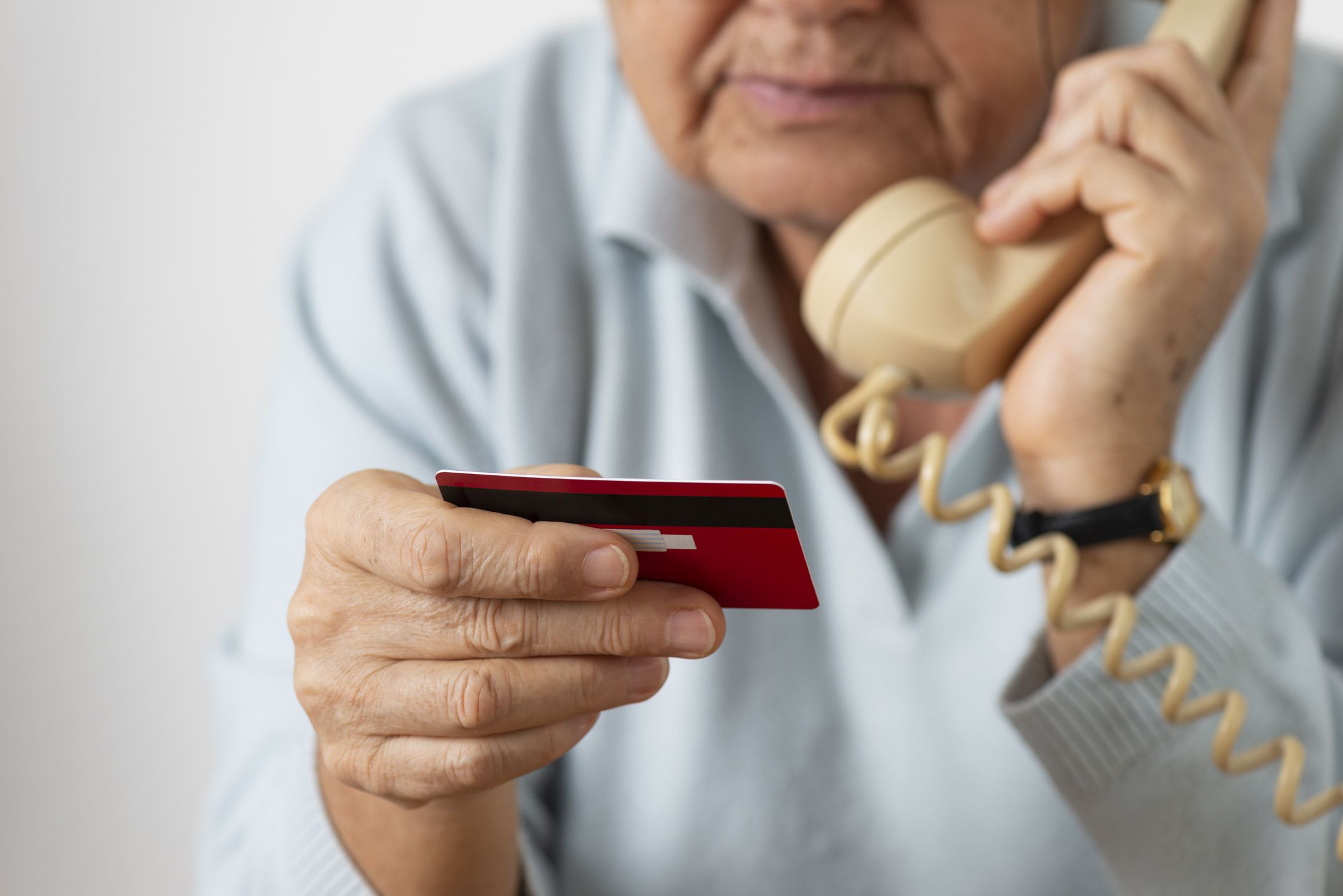Senior woman using phone while holding credit card.