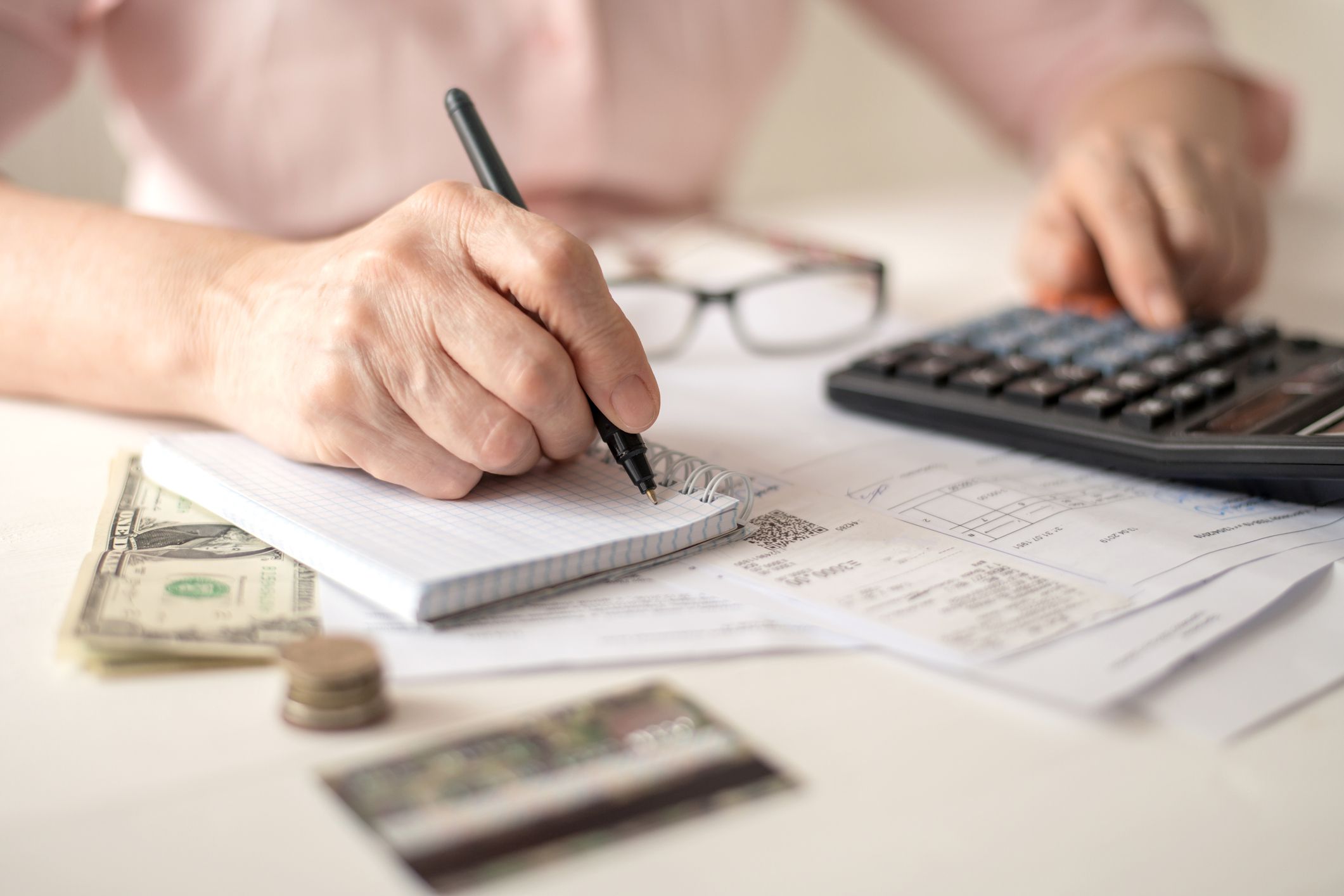 Pension calculation concept, old hands counting finances on a home calculator ,