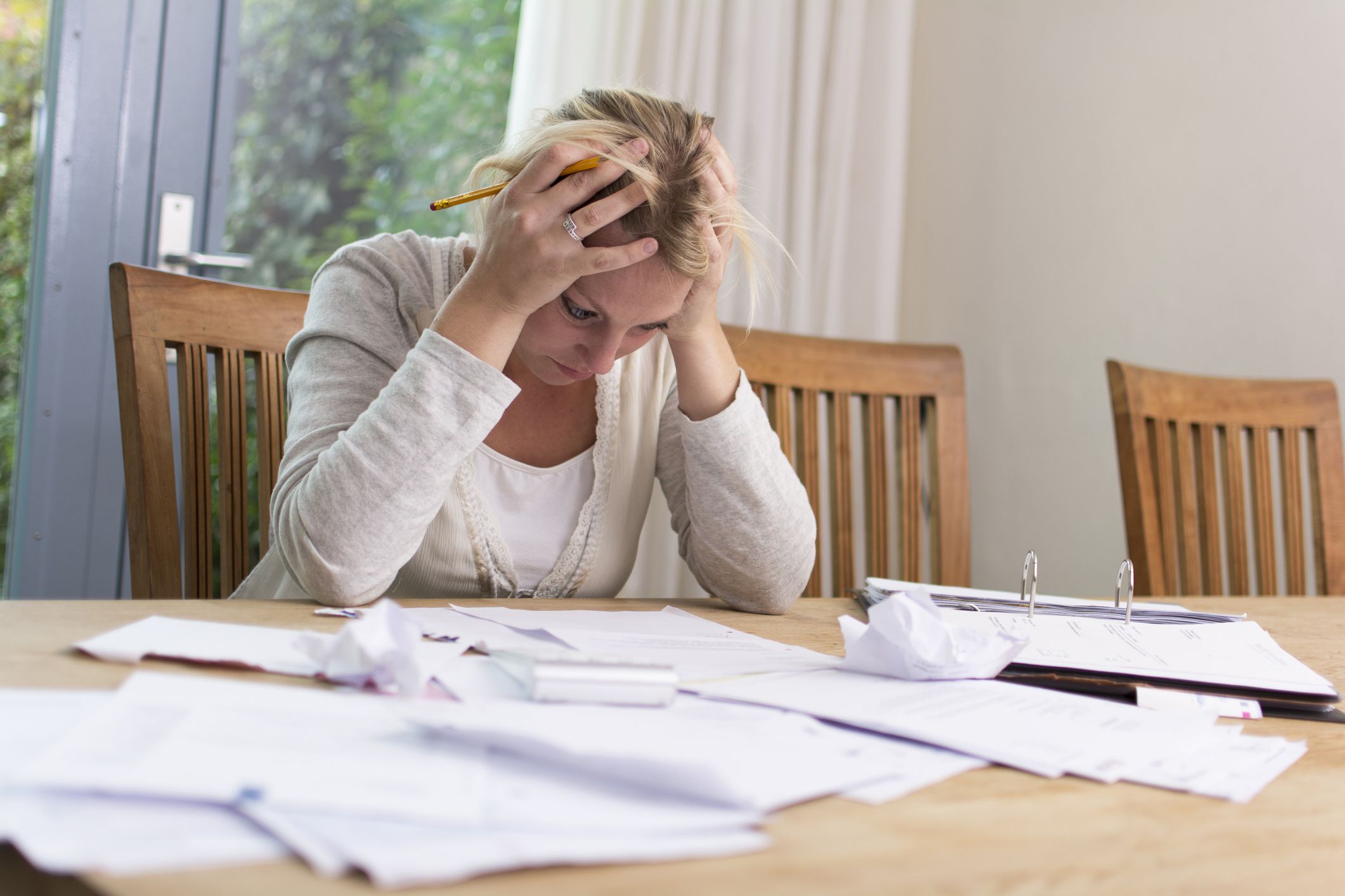 woman with heads in hands looking frazzled looking at bills