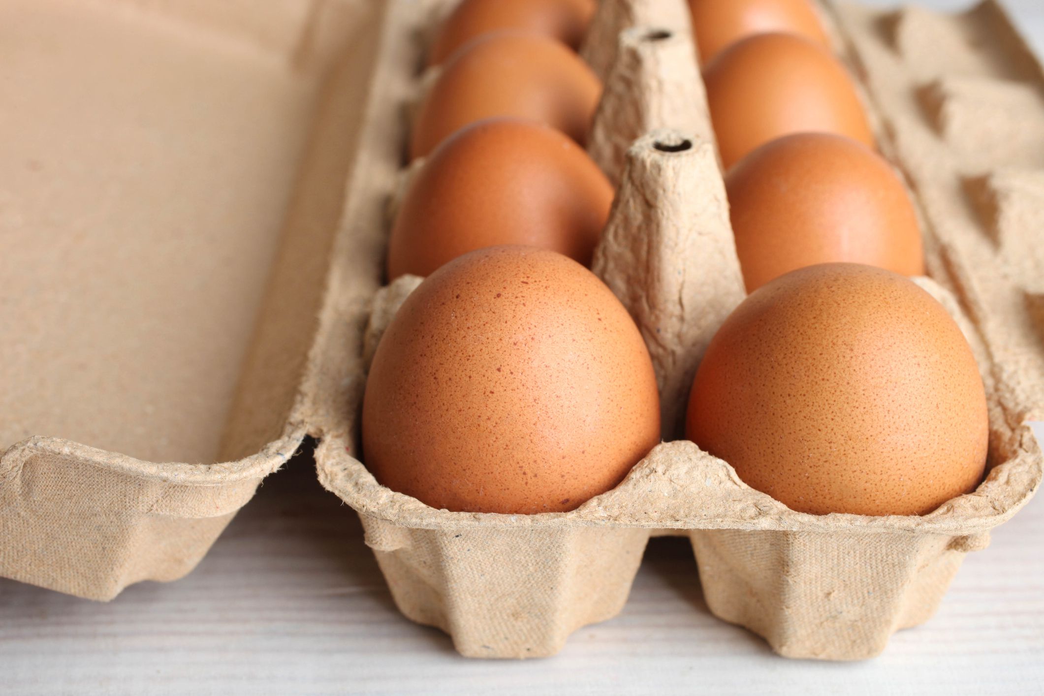 Brown chicken eggs in a box for eggs on a wooden background.
