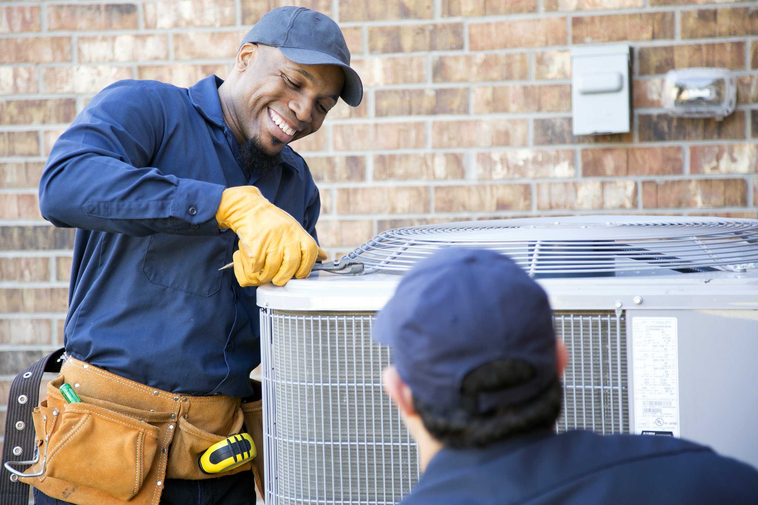 multi-ethnic team of blue collar air conditioner repairmen at work