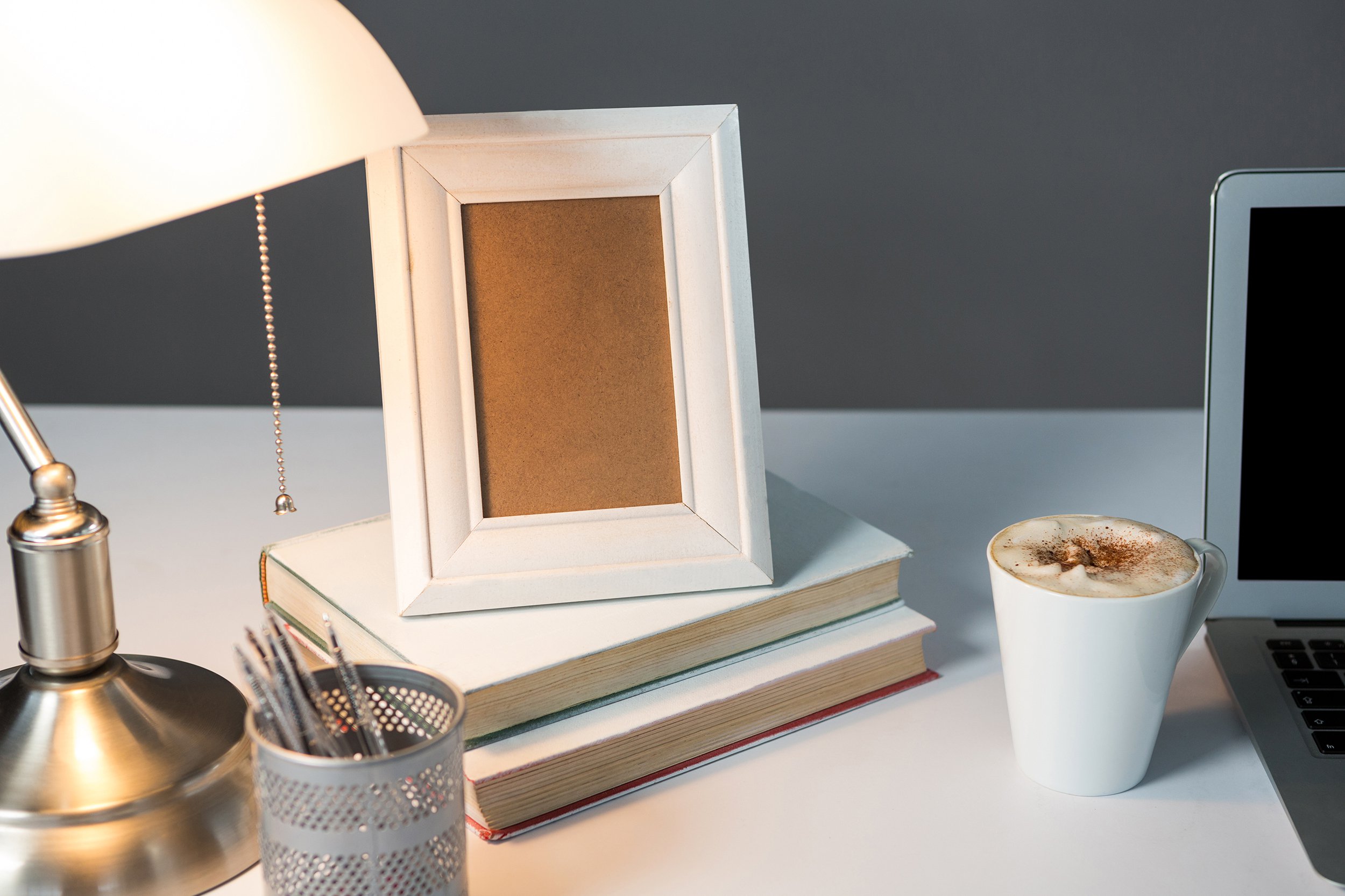 picture frame, cup of coffee with books and table lamp