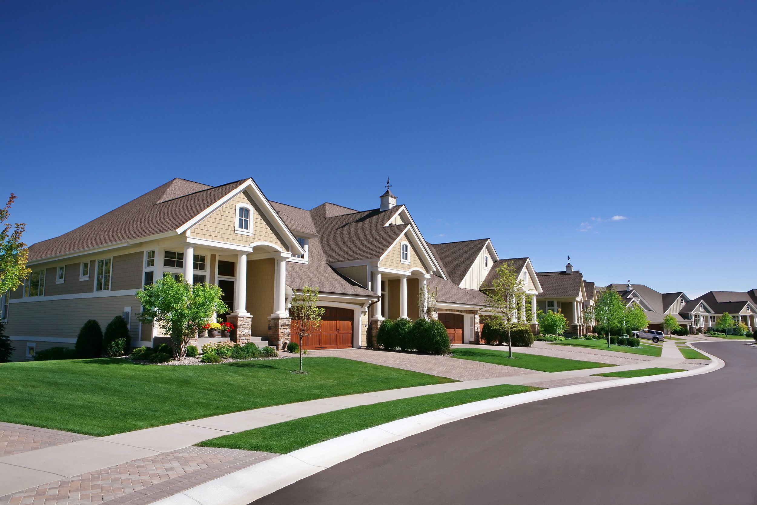 homes on perfectly manicured typical American suburban street on a beautiful clear September day
