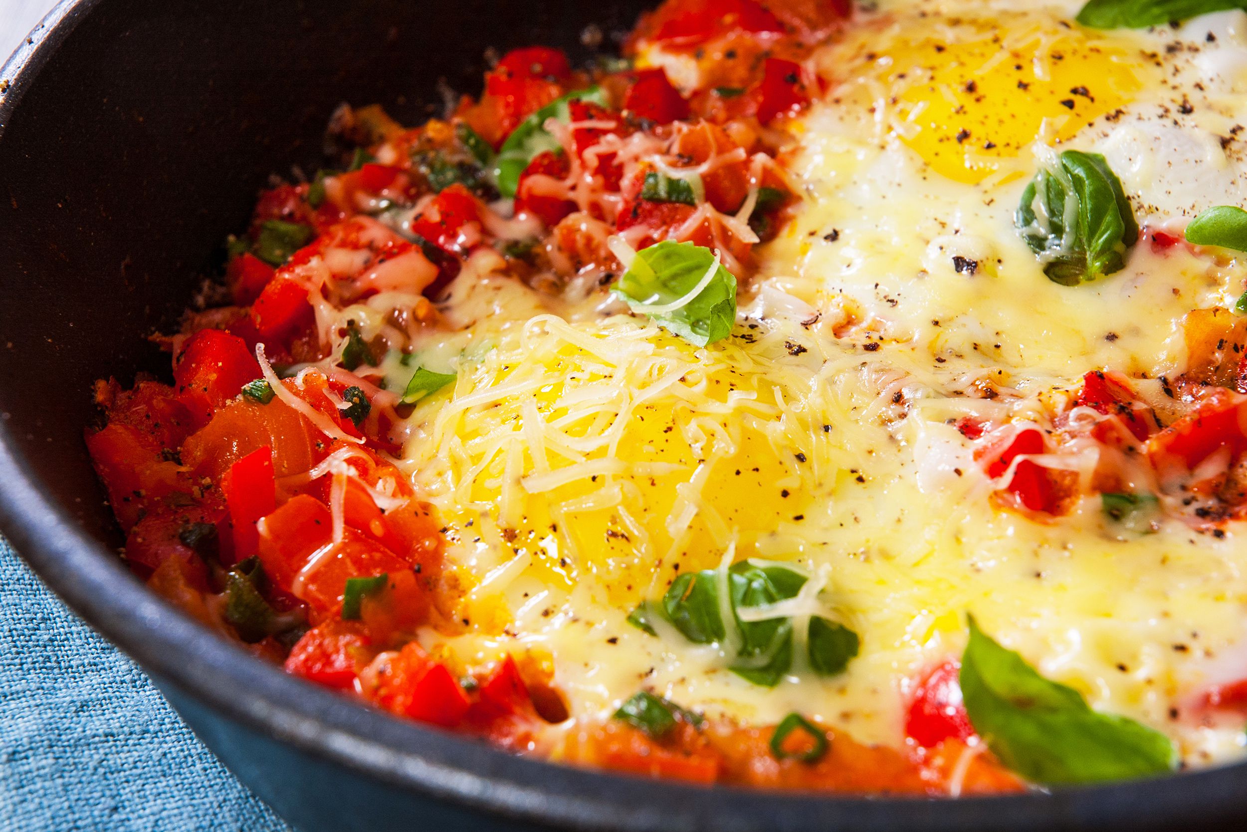 Closeup of shakshuka in a cast iron skillet with a blue napkin in the lower left corner