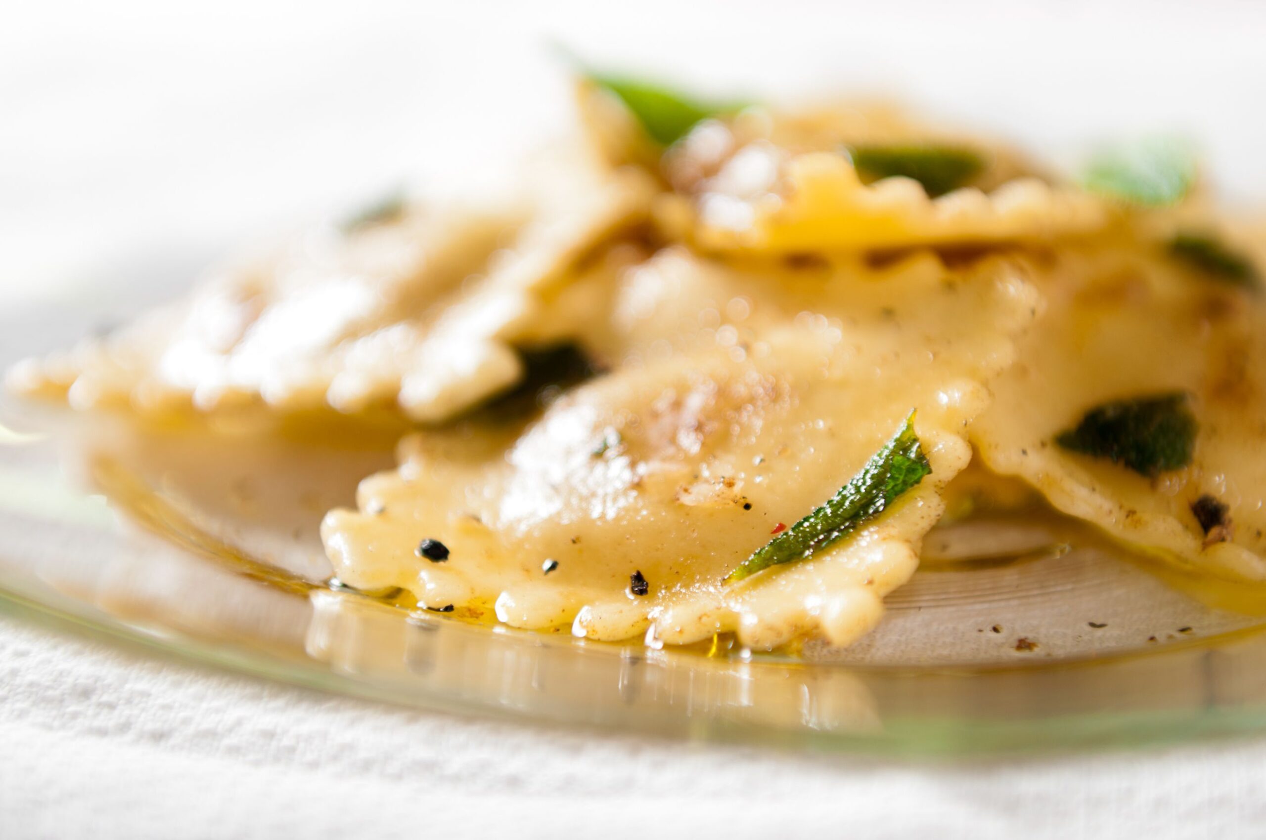 Closeup of a pile of wonton ravioli on a glass plate on a white napkin with a blurred white background