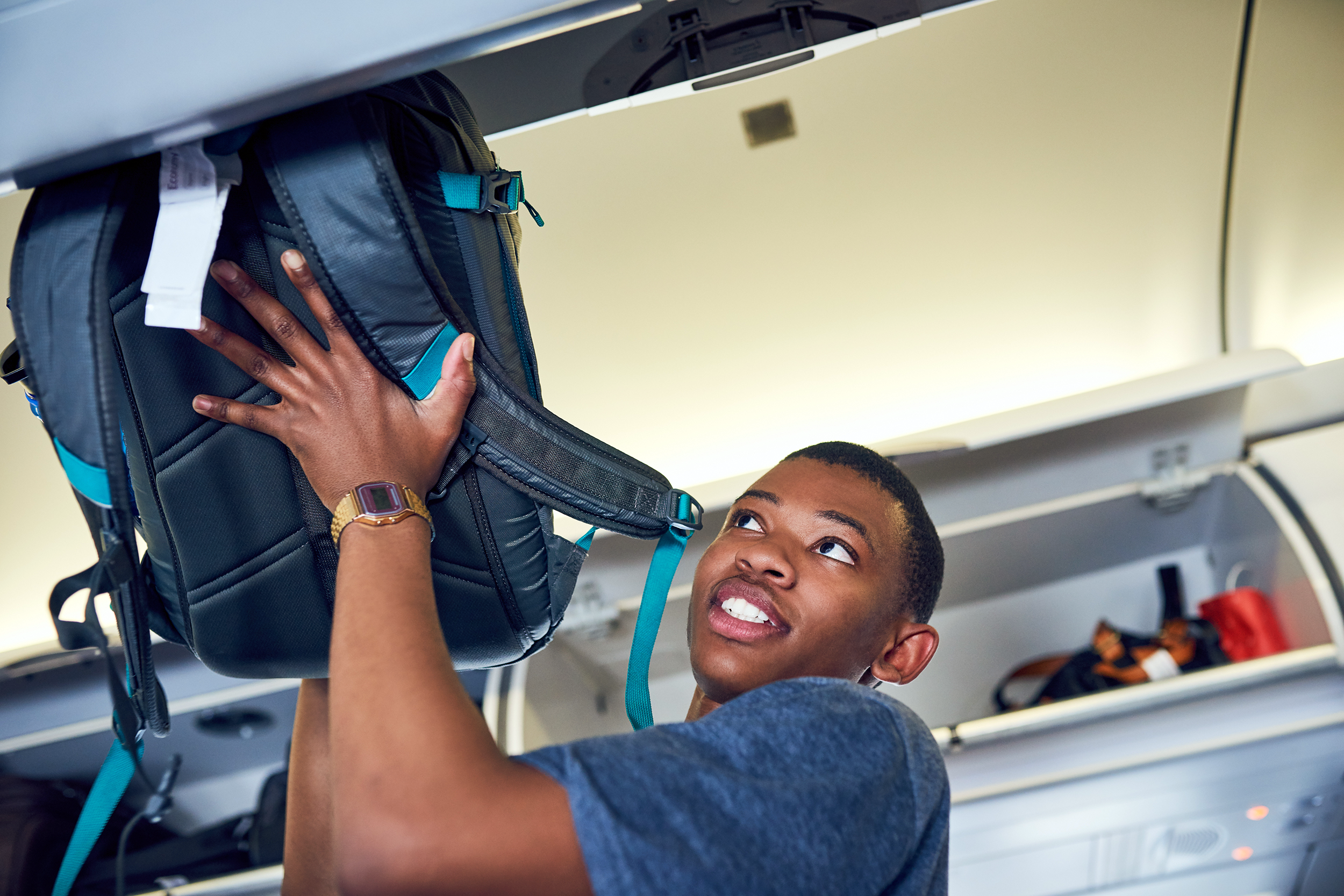 Man stowing his overhead luggage on a plane