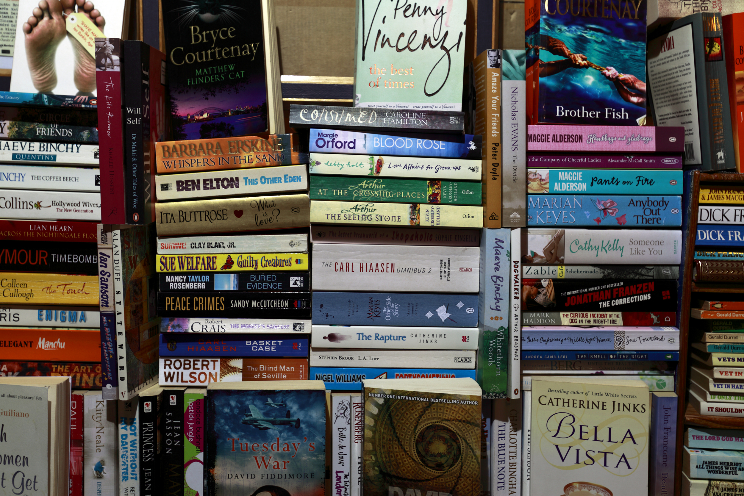 Focus on several piles of paperback books in English and different genre, paperback books fill the entire image