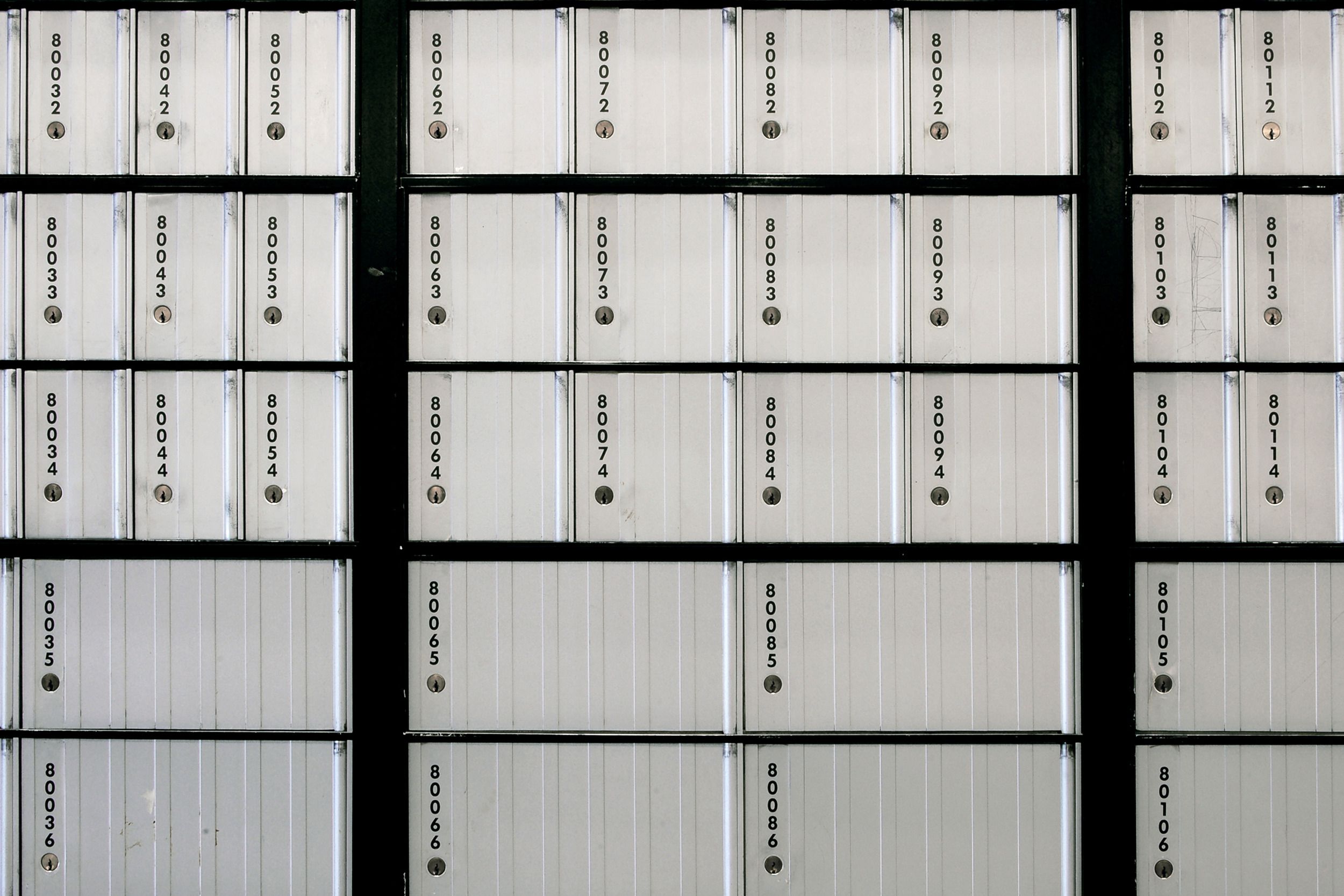 silver colored Post Office boxes both small on top three rows and large on bottom two rows
