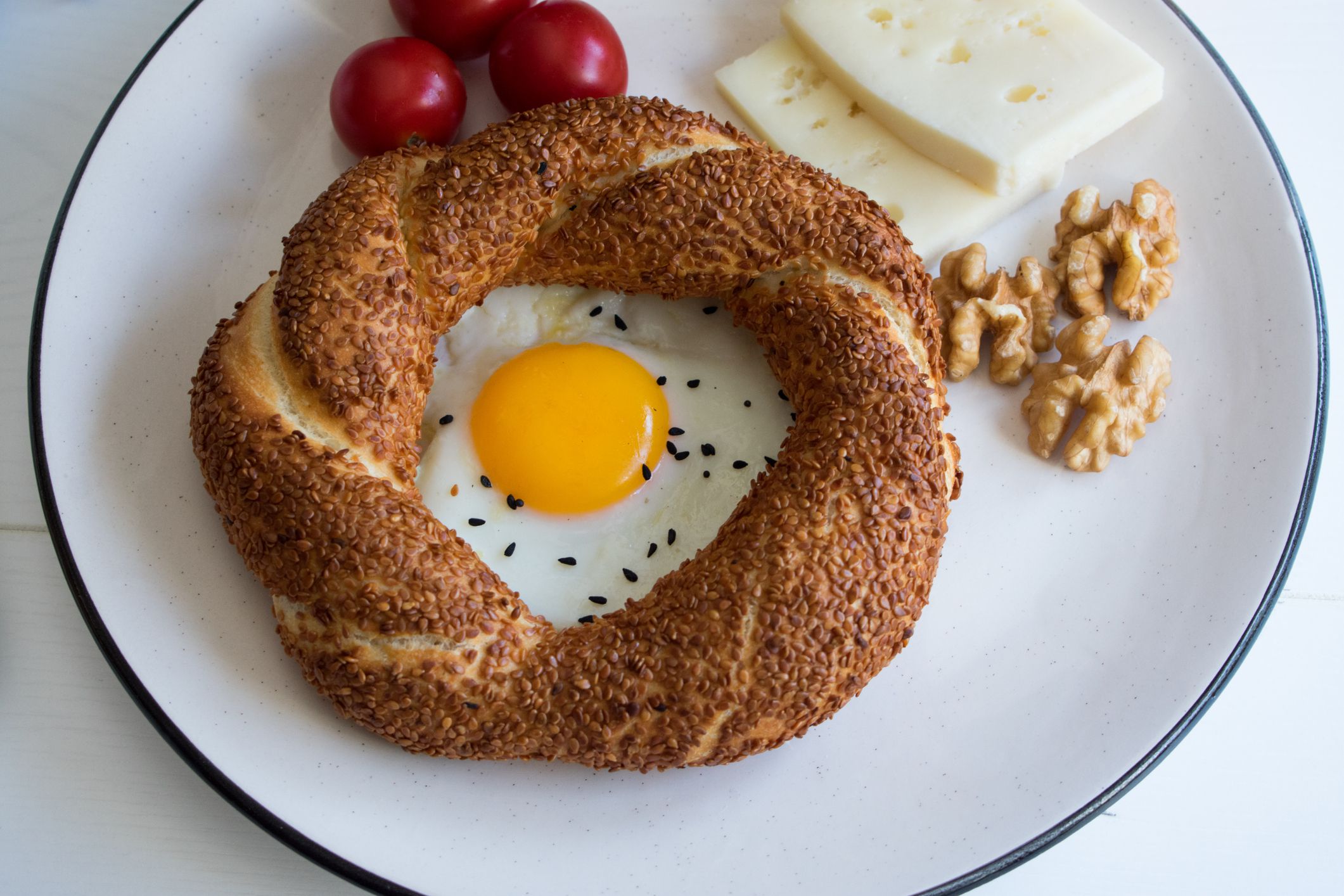 Delicious breakfast plate consisting of bagels, eggs, cheese, walnuts and tomatoes