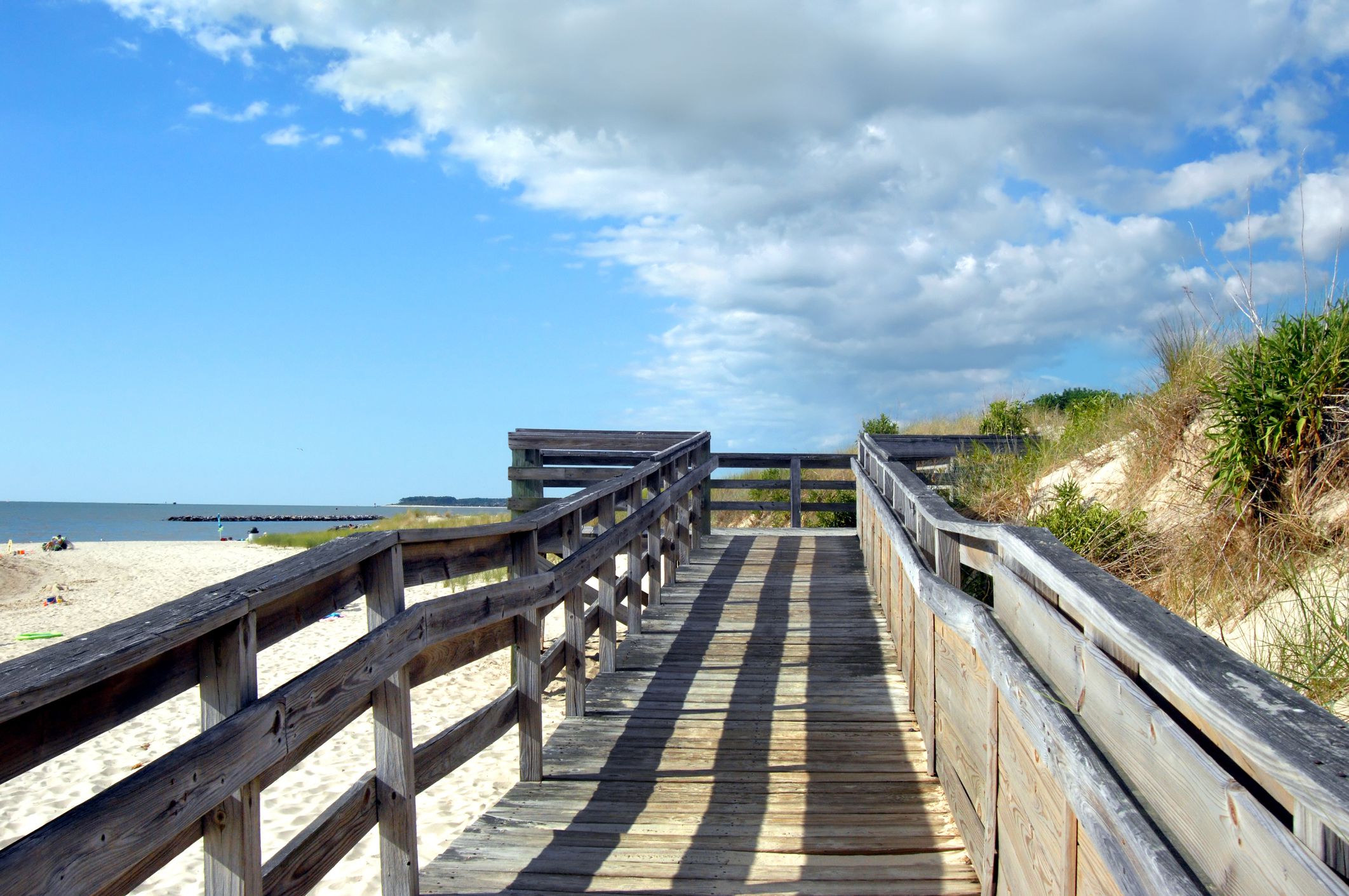 Wooden dock, with late afternoon shadows, partition off sand dunes from Cape Charles Beach on the Island of Assateague, Virginia.