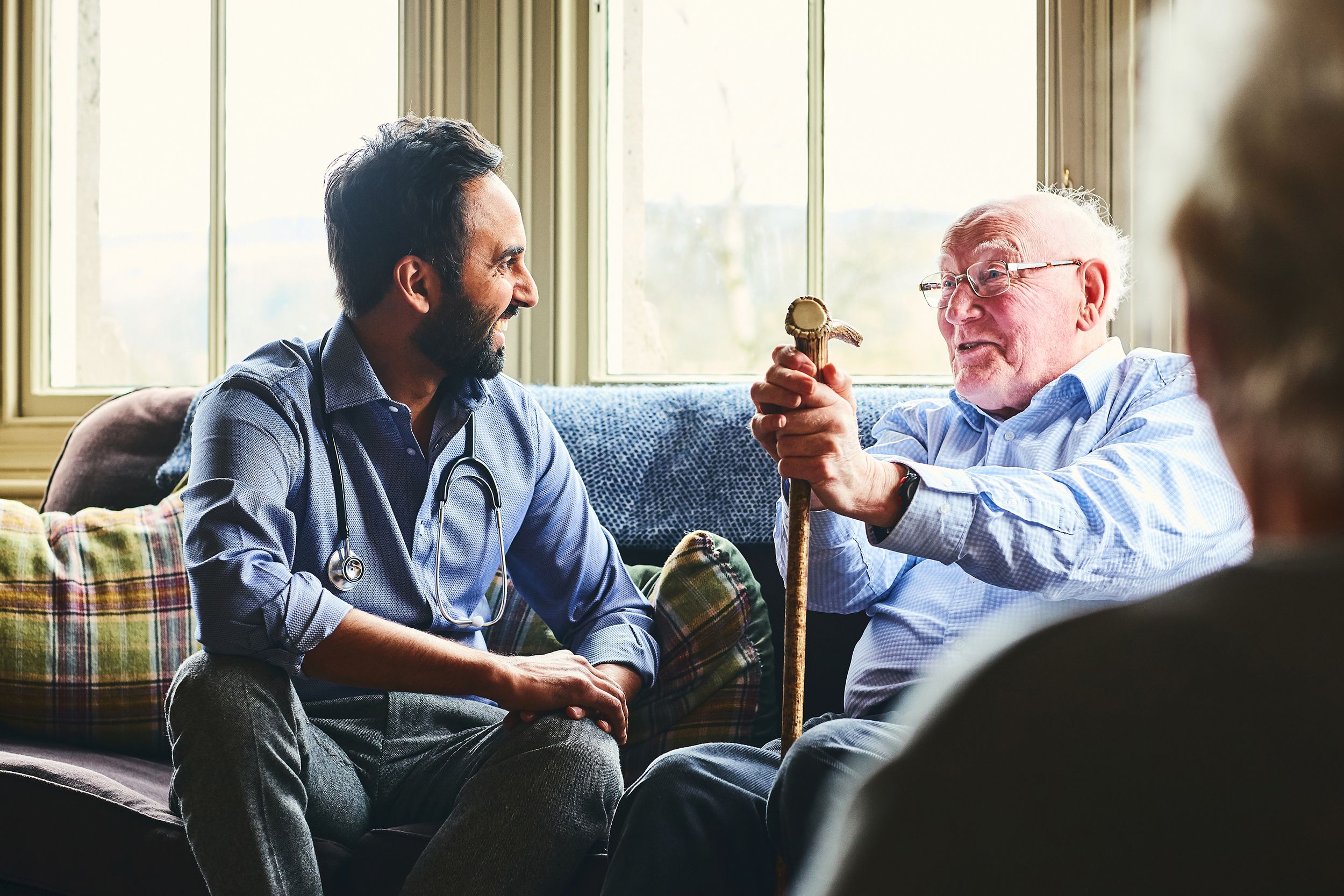 smiling doctor visiting senior man at home