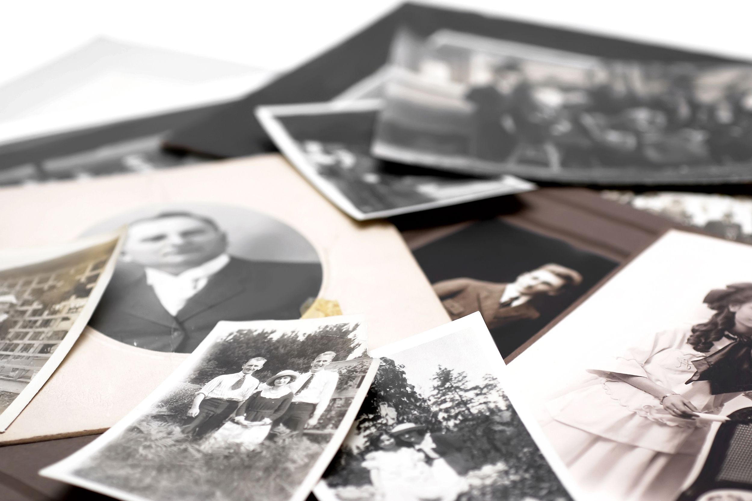 A pile of vintage black and white family photos with a blurred background of white