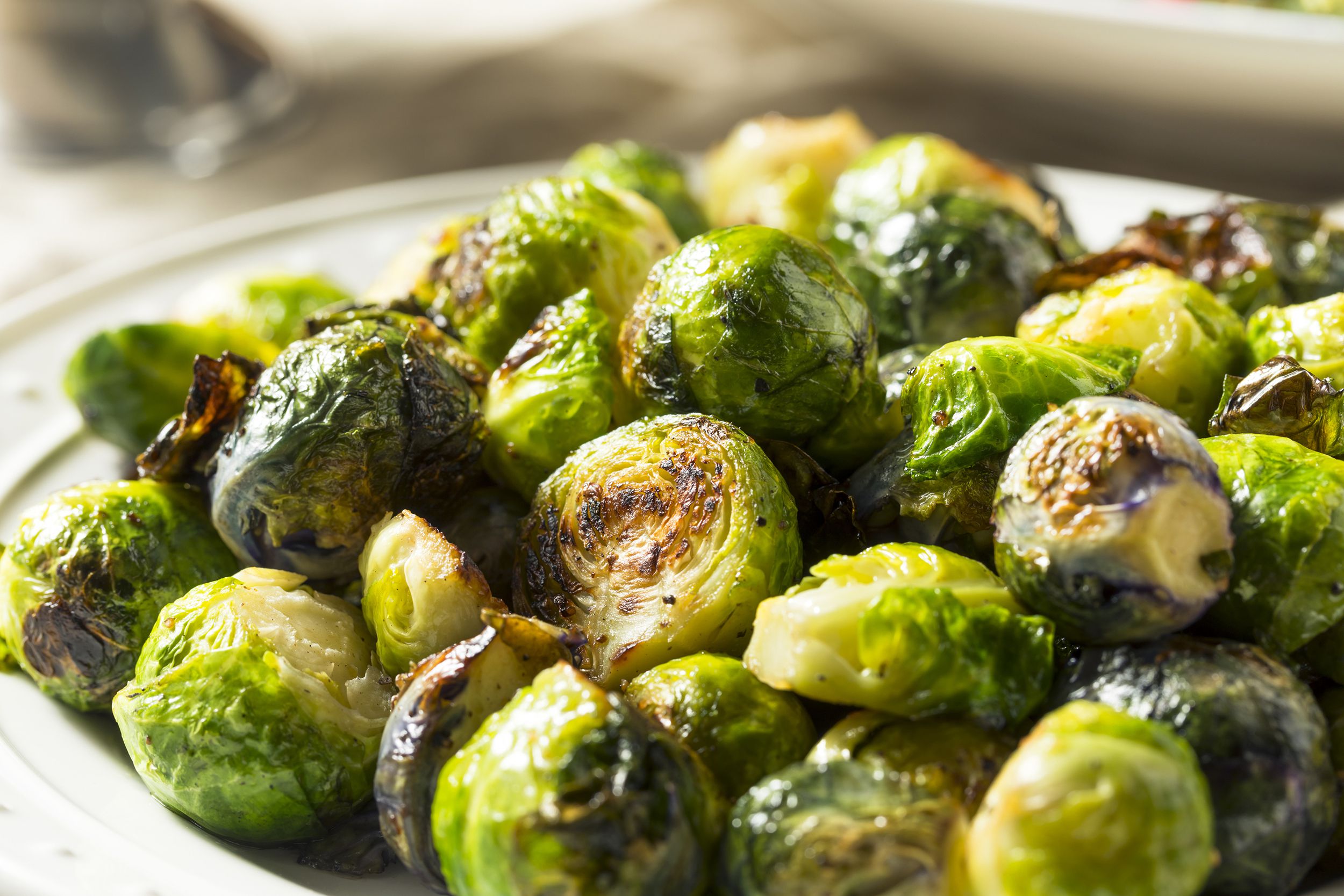 Closeup of air fried brussels sprouts in a white plate with blurred background